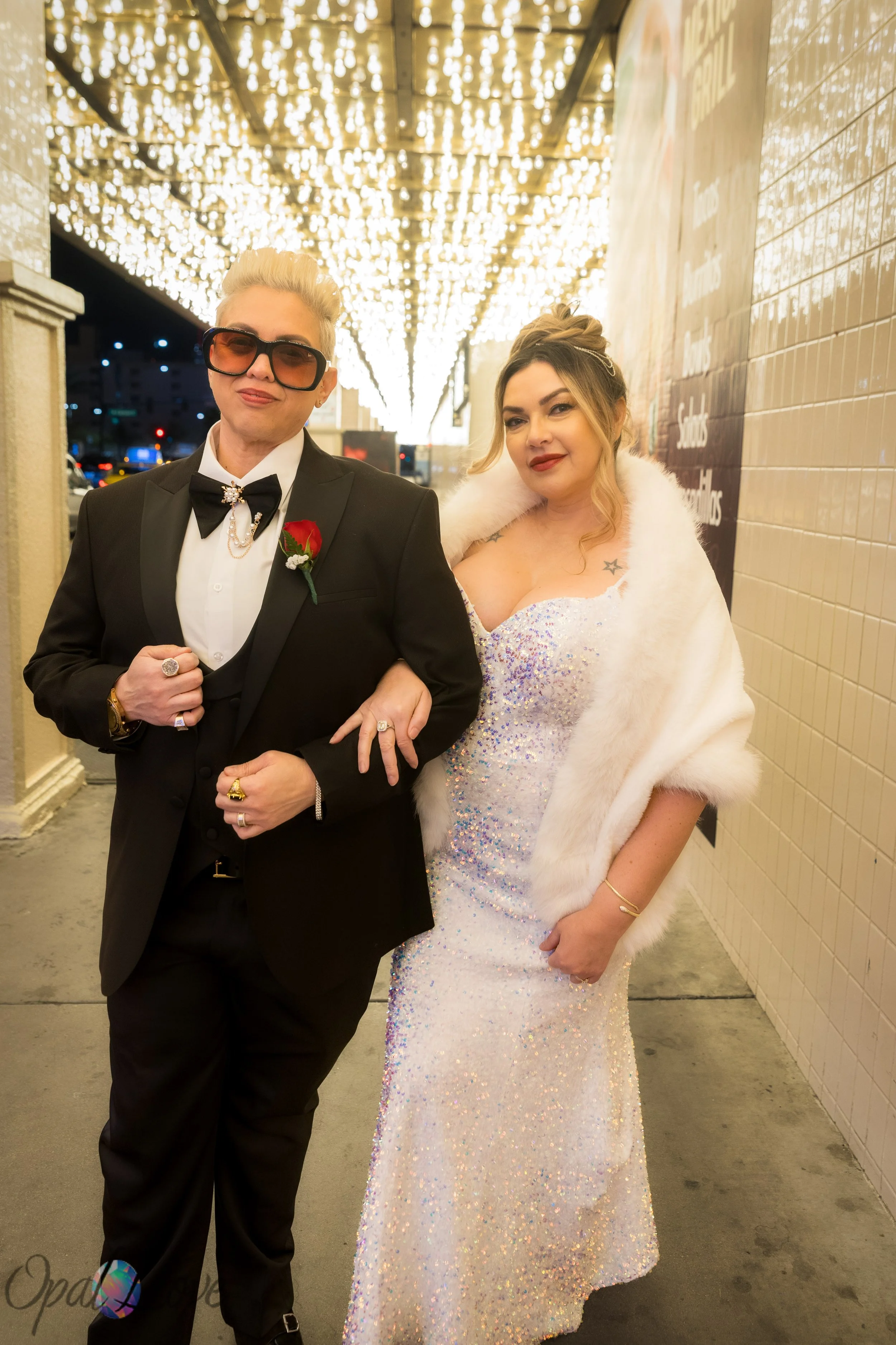 Anniversary couple walking arm in arm under classic Fremont Street marquee lights in downtown Las Vegas.