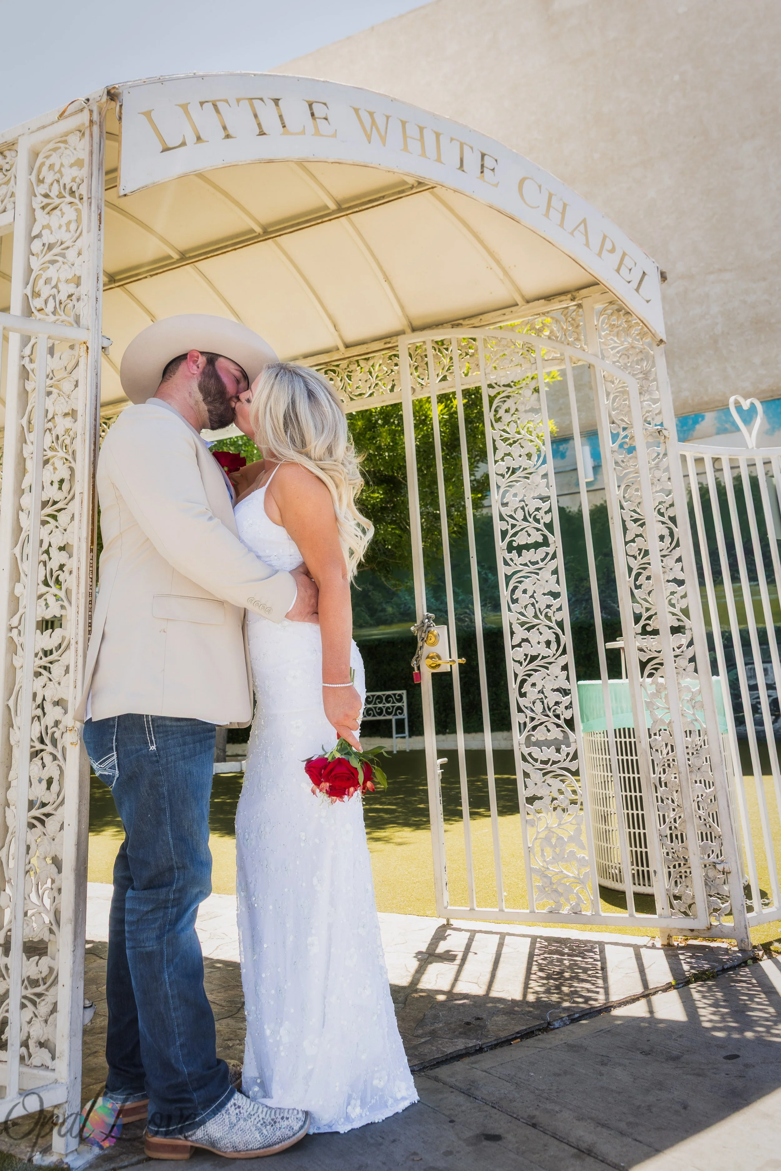 Bride and groom kissing beneath the ornate chapel entrance at Little White Wedding Chapel in Las Vegas