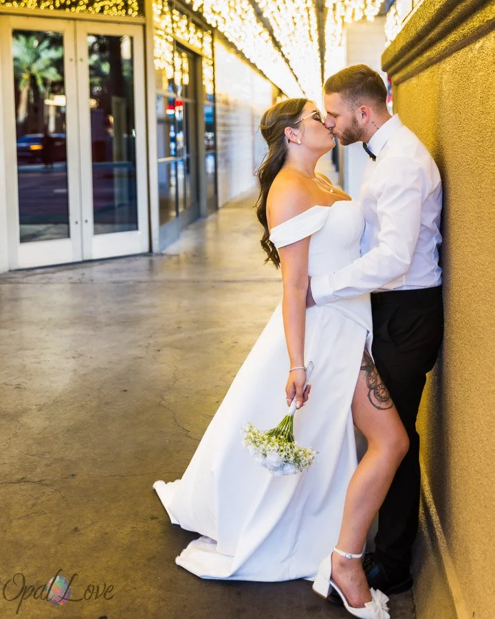Newlywed couple kissing beneath marquee lights on Fremont Street in downtown Las Vegas.