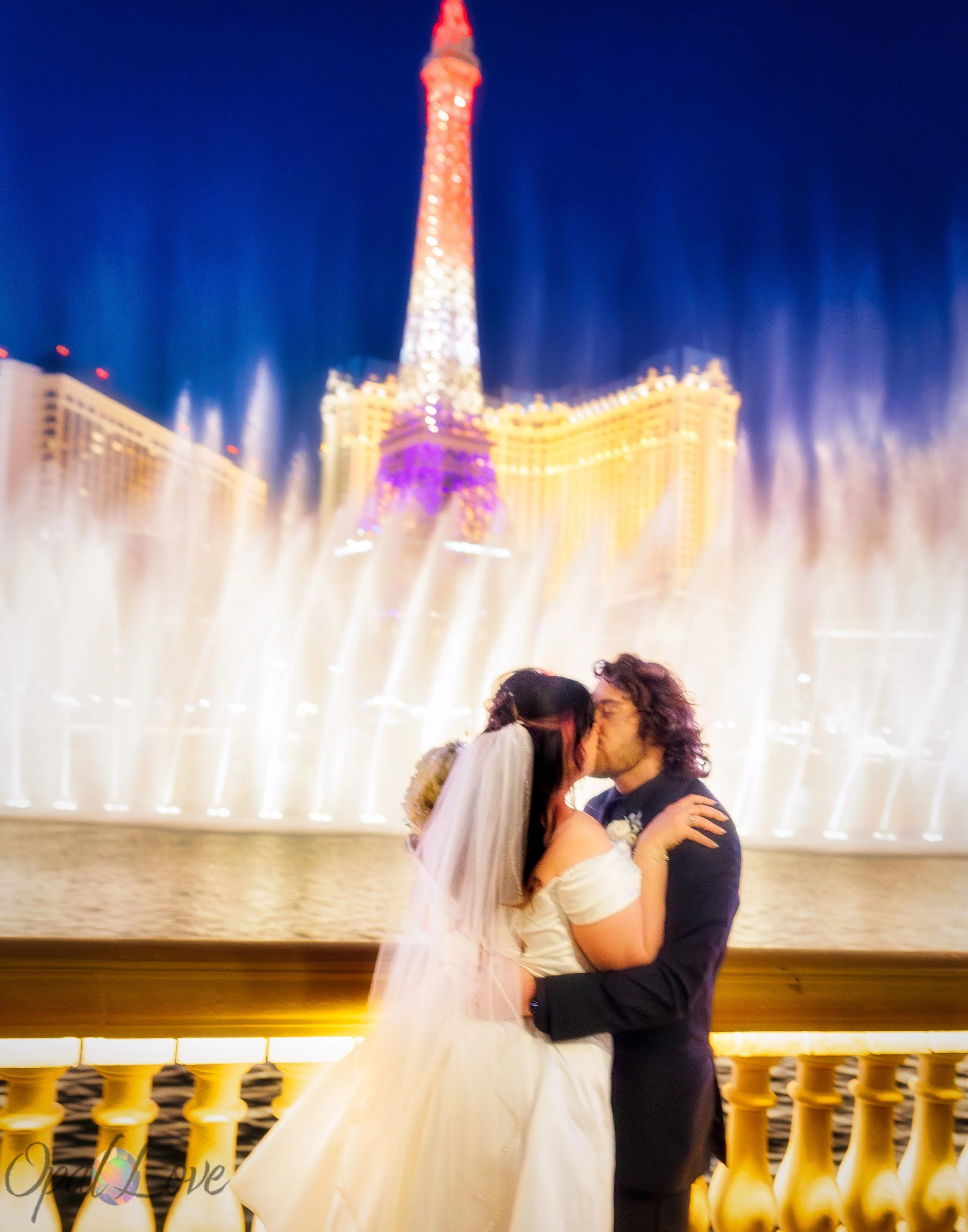 Couple sharing a quiet moment outside the Bellagio fountains with the Paris Las Vegas tower in the distance captured by Opal Love Photography.