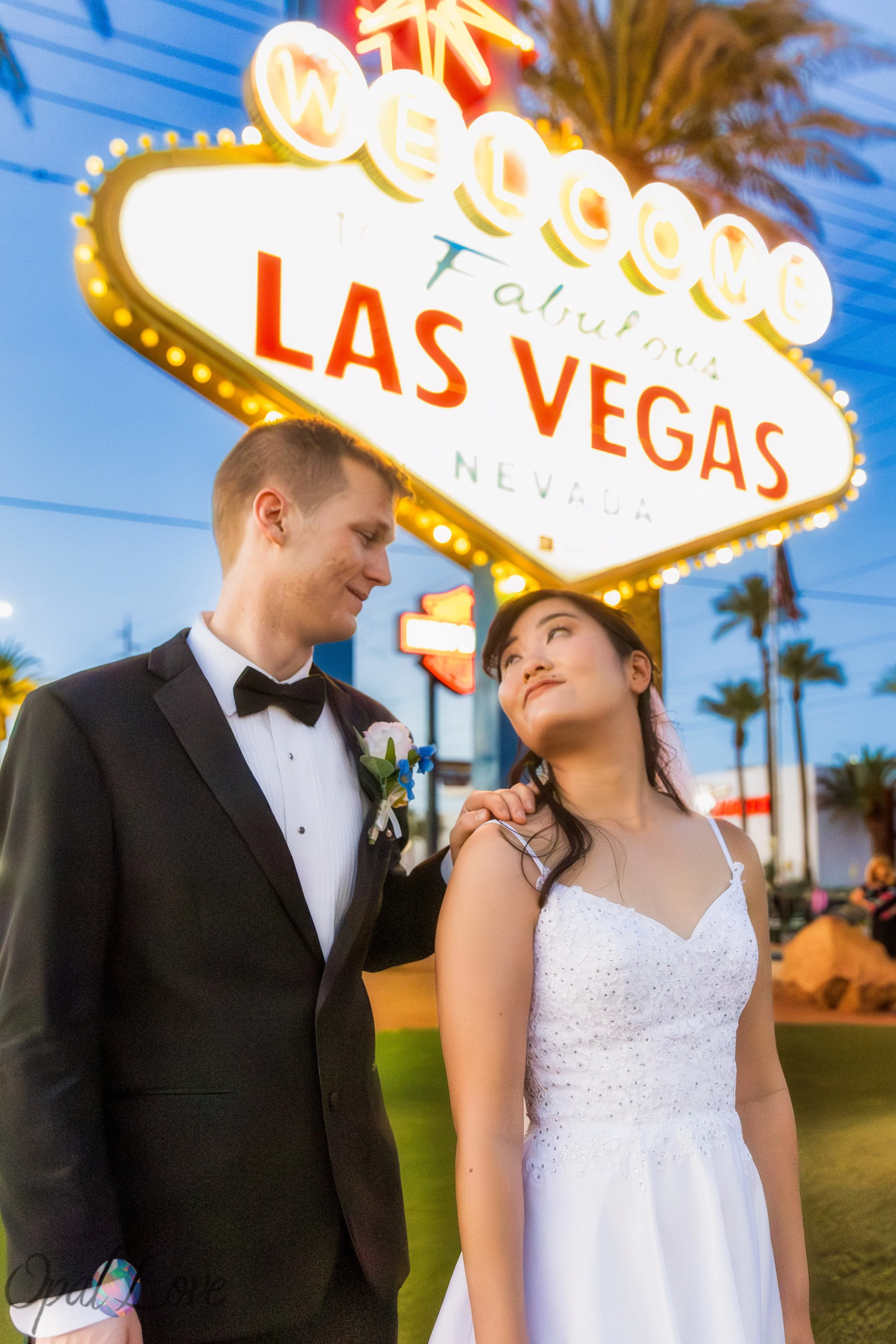 Bride and groom posing in front of the Welcome to Fabulous Las Vegas sign at sunset.