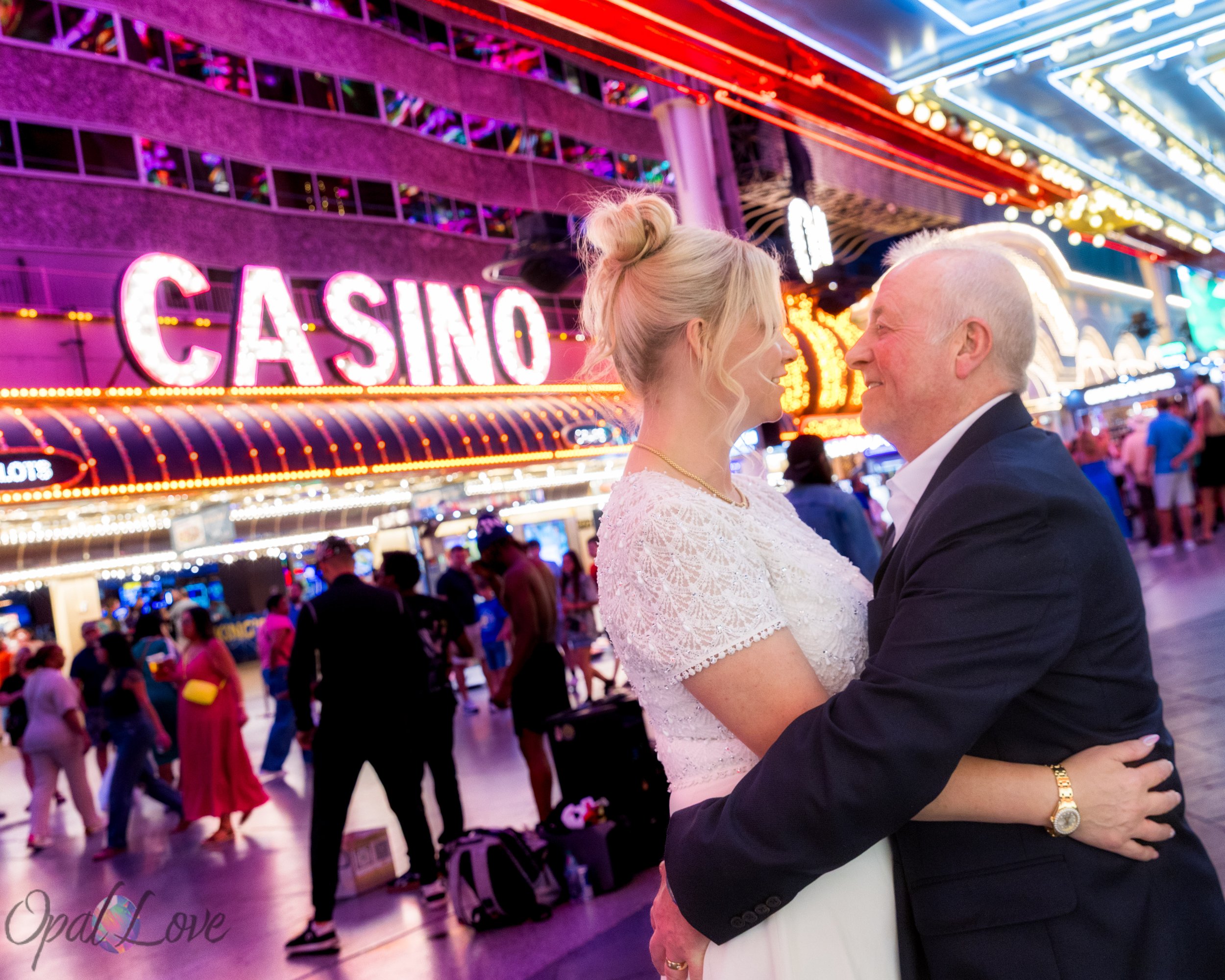 Couple embracing under colorful lights during a Fremont Street Las Vegas elopement photo session.