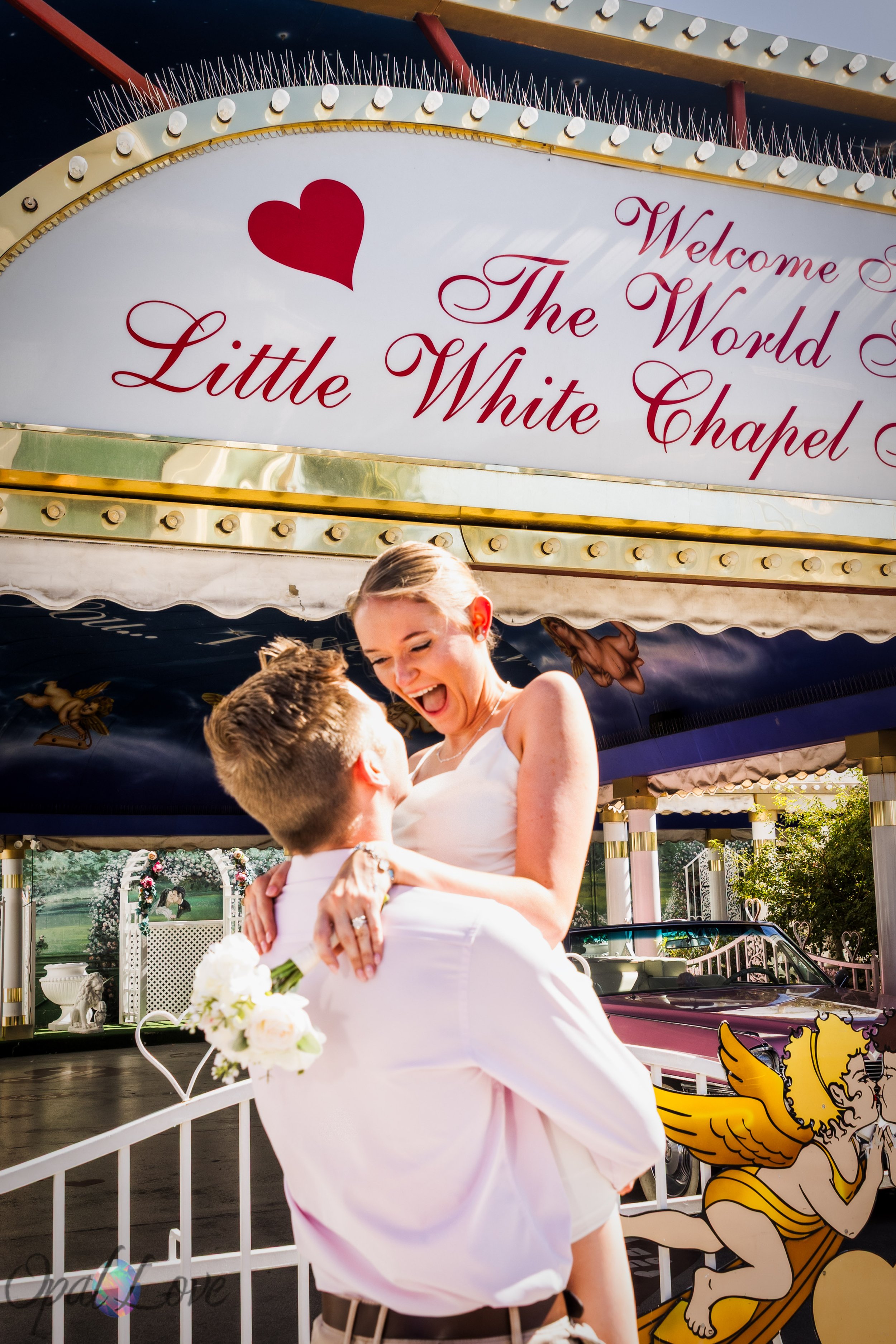 Ryan lifting Katie beneath the Little White Wedding Chapel marquee during their Las Vegas vow renewal photos.
