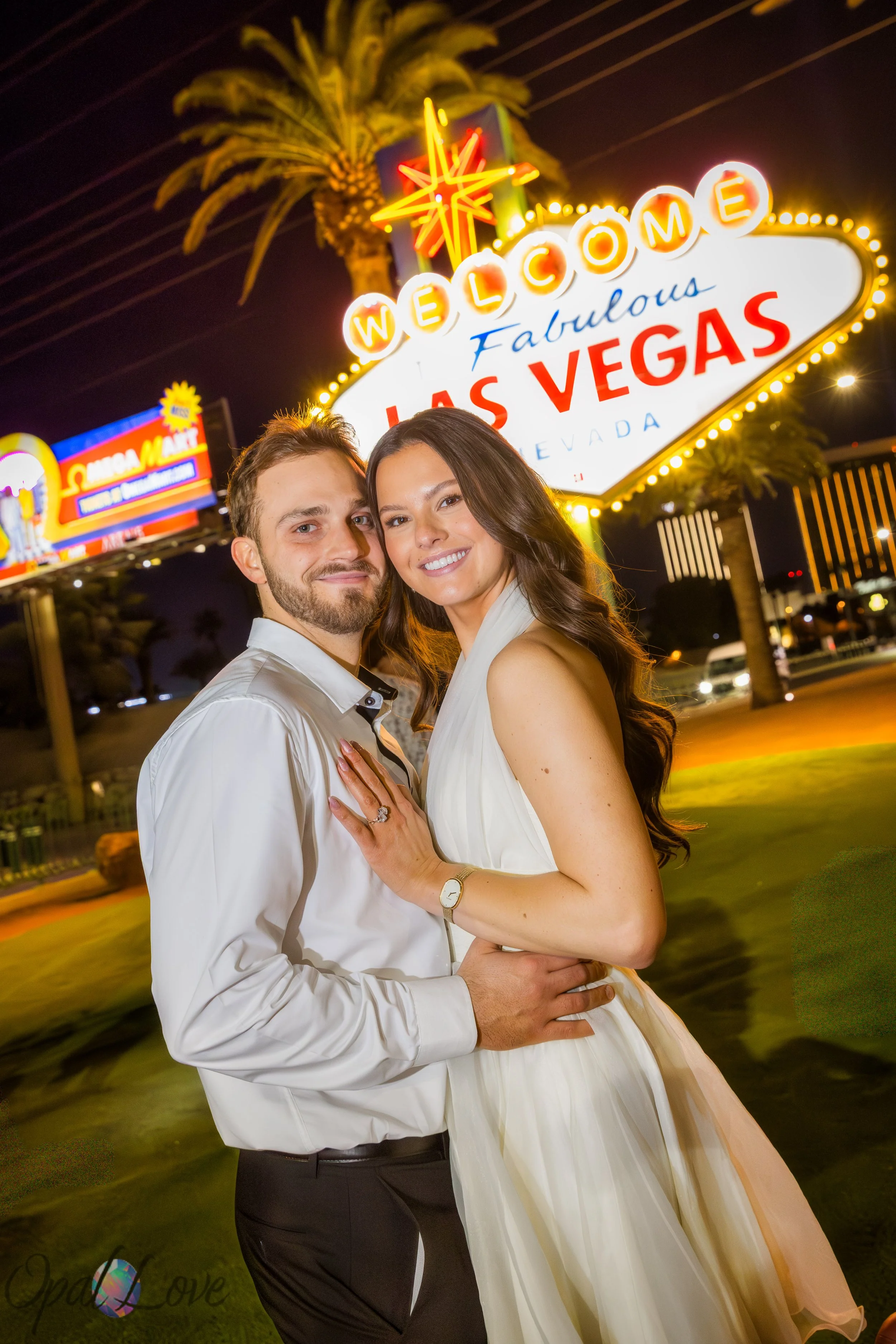Couple embracing in front of the Welcome to Fabulous Las Vegas sign at night after their chapel ceremony.
