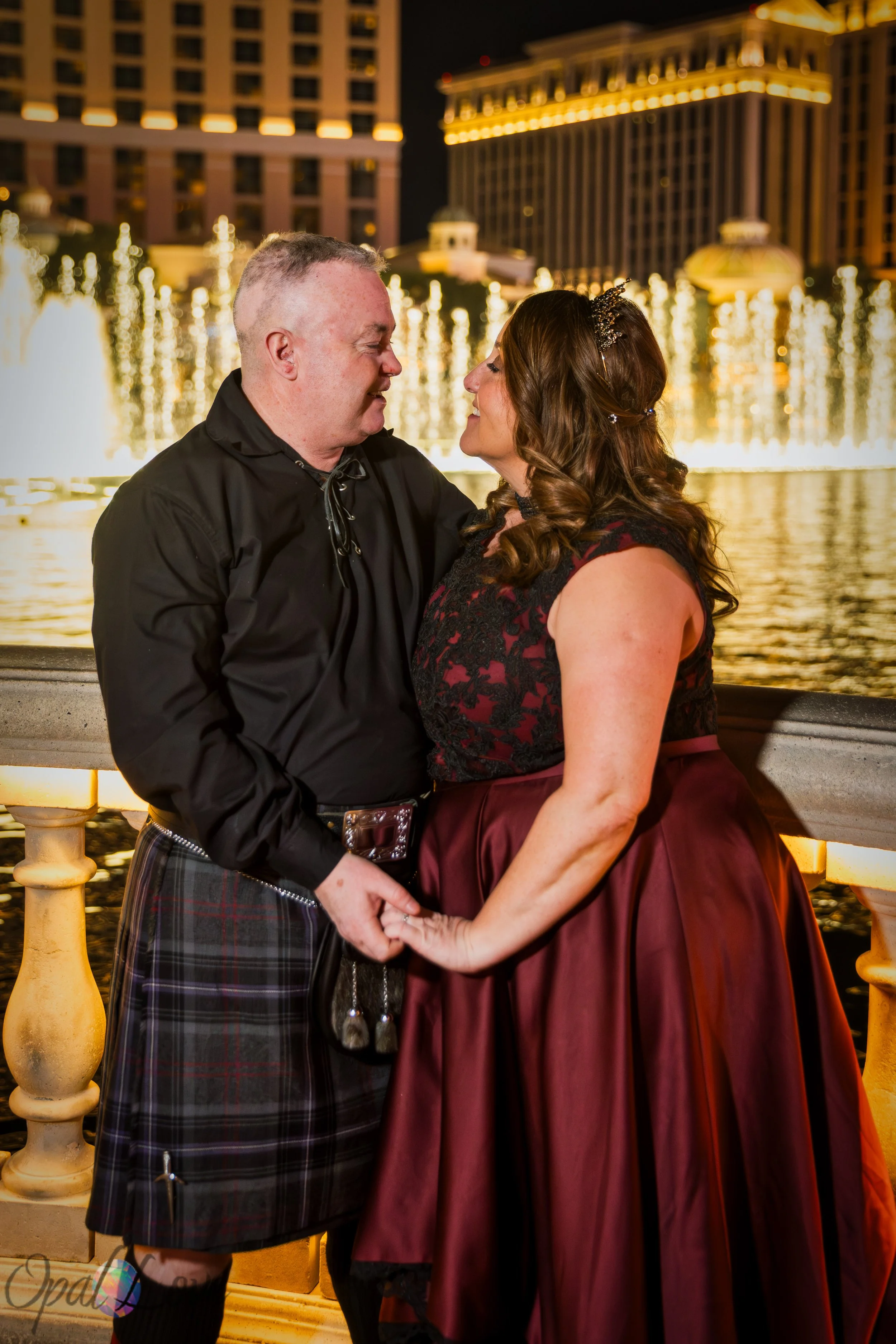 Newly married couple holding hands beside the Bellagio Fountains at night on the Las Vegas Strip.