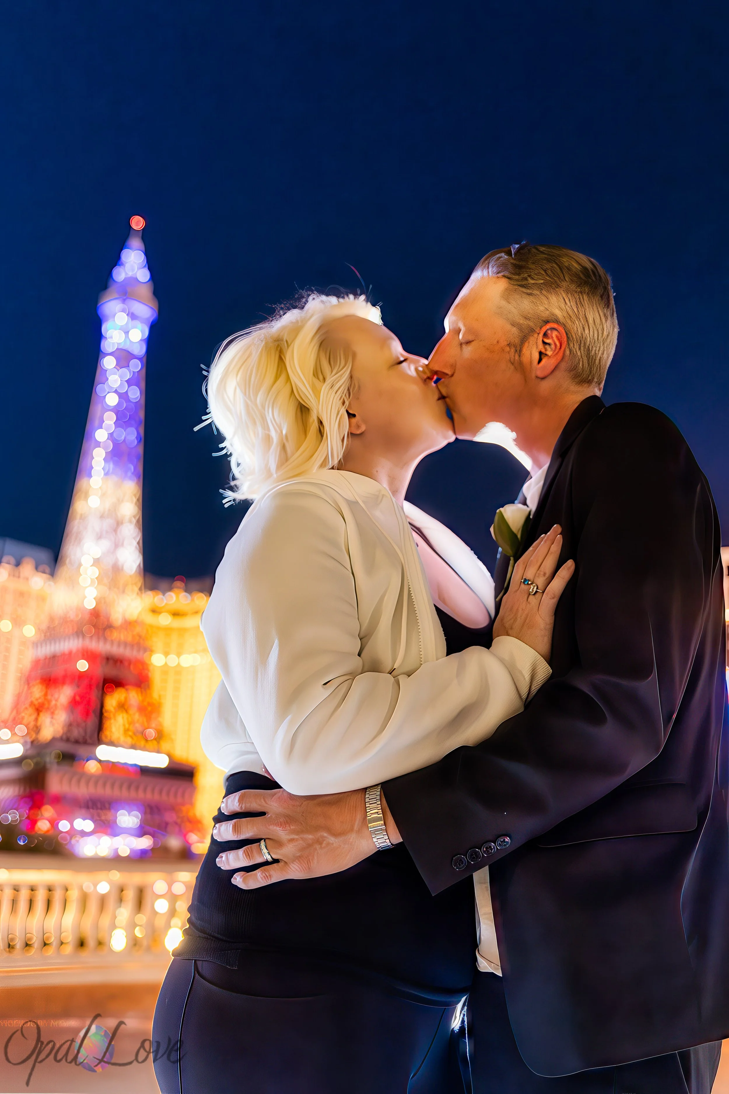 Close up kiss at Paris Las Vegas with glowing Eiffel Tower lights behind the couple