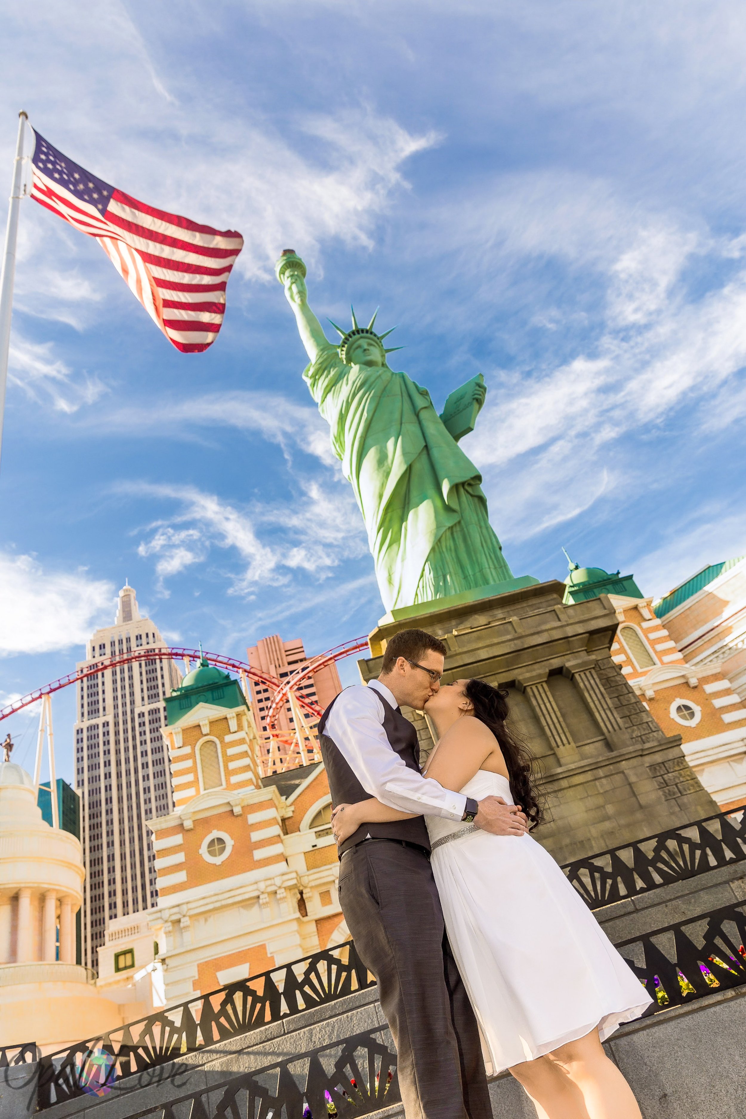 Newlyweds kiss beneath the Statue of Liberty with the Brooklyn Bridge architecture at New York-New York Las Vegas.