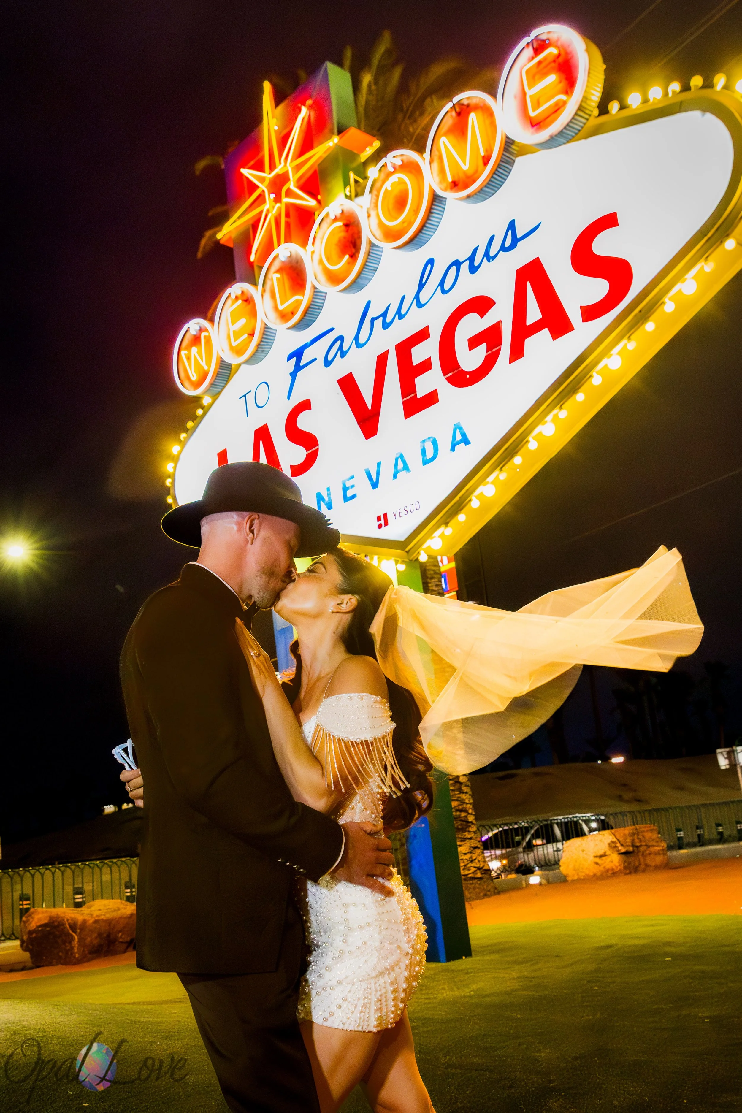 Bride and groom kissing at Welcome to Las Vegas Sign at night