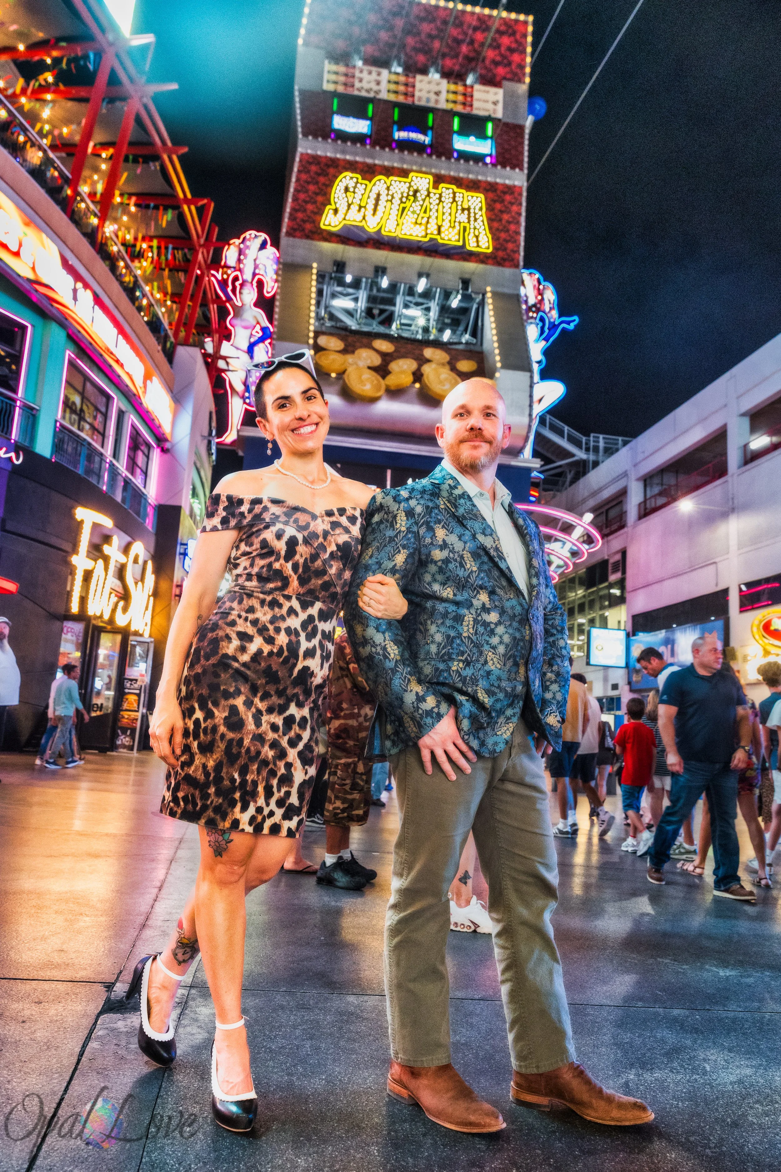 Maddie and Ashley posing near SlotZilla surrounded by neon lights during their Fremont Street photo session in Downtown Las Vegas.