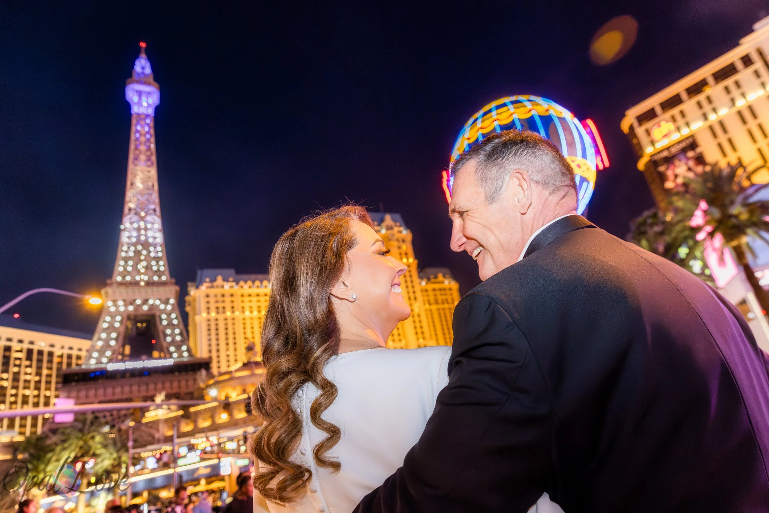 Couple walking together at Paris Las Vegas with Eiffel Tower lit up at night