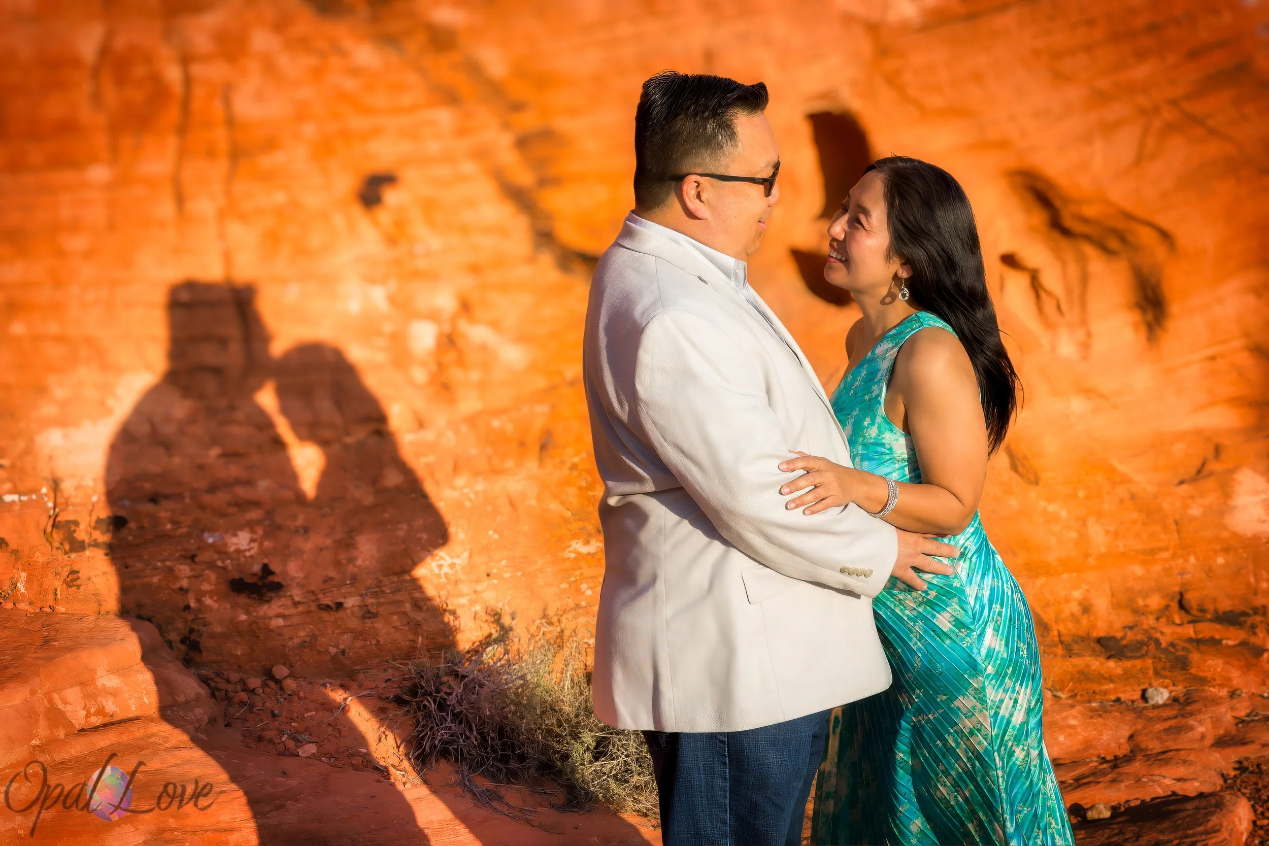 Couple embraces beside glowing red rock formations in the Nevada desert