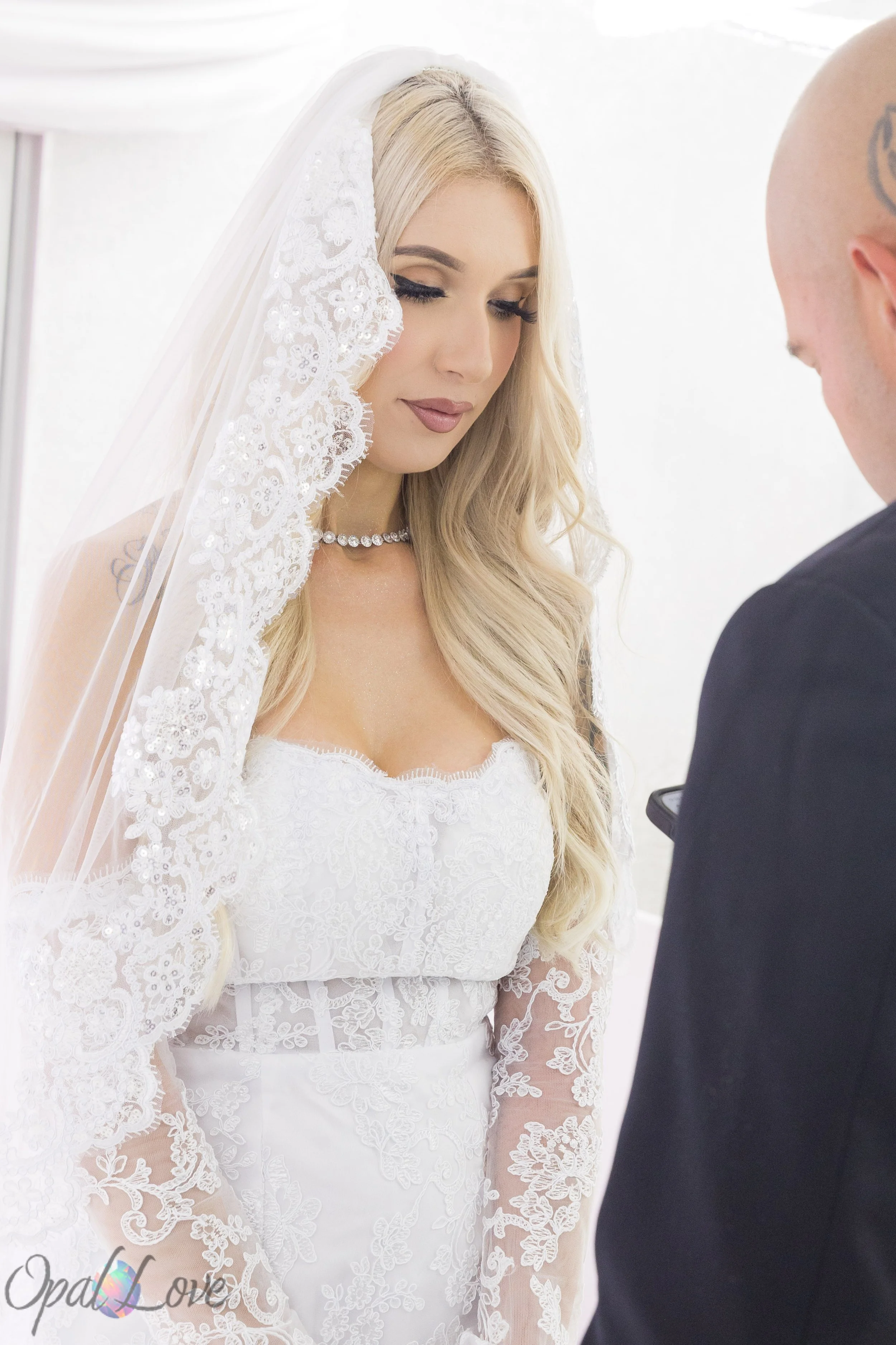 Bride in a lace veil looking down during her wedding ceremony.
