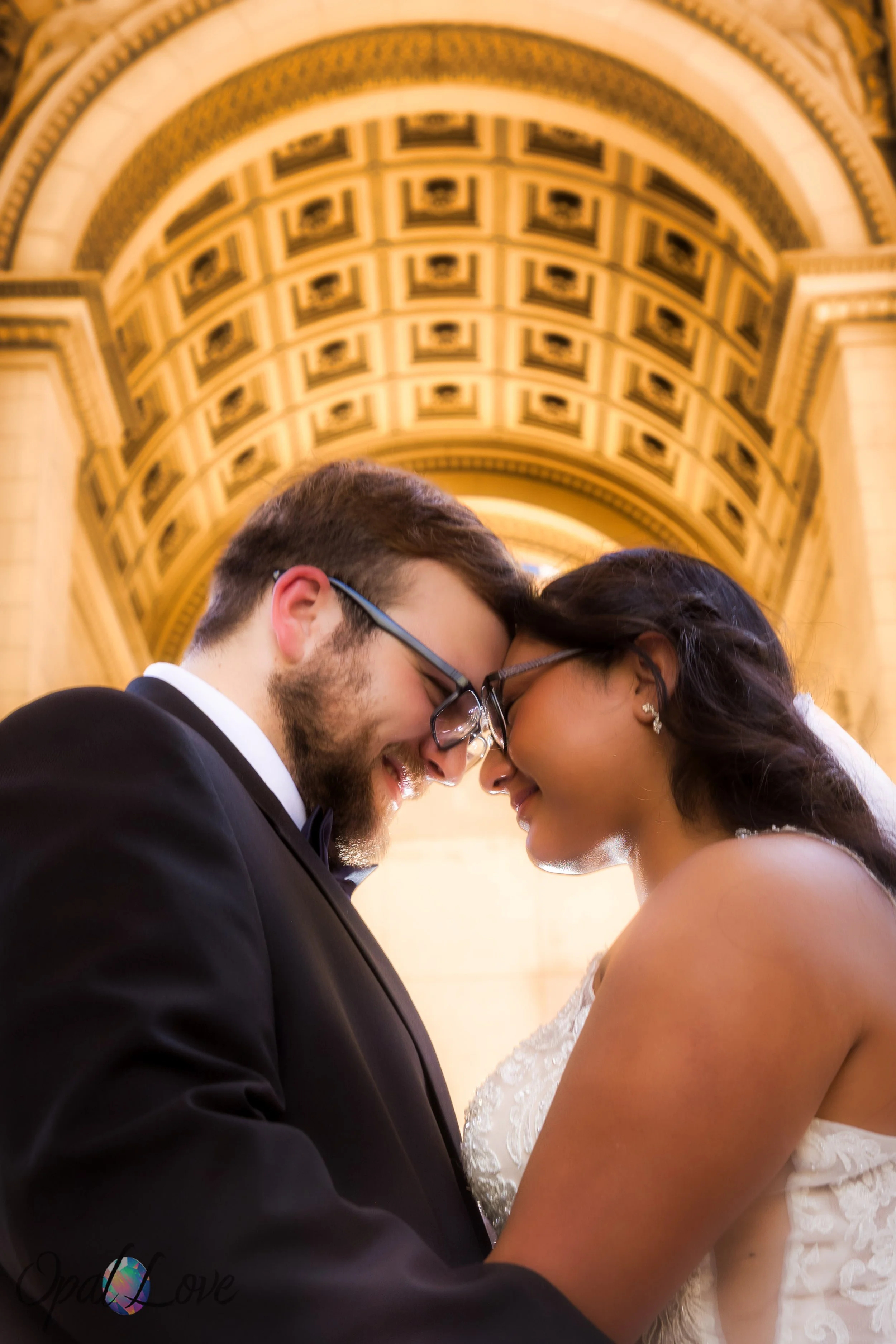 Bride and groom standing close under Paris Las Vegas arch with golden tones.