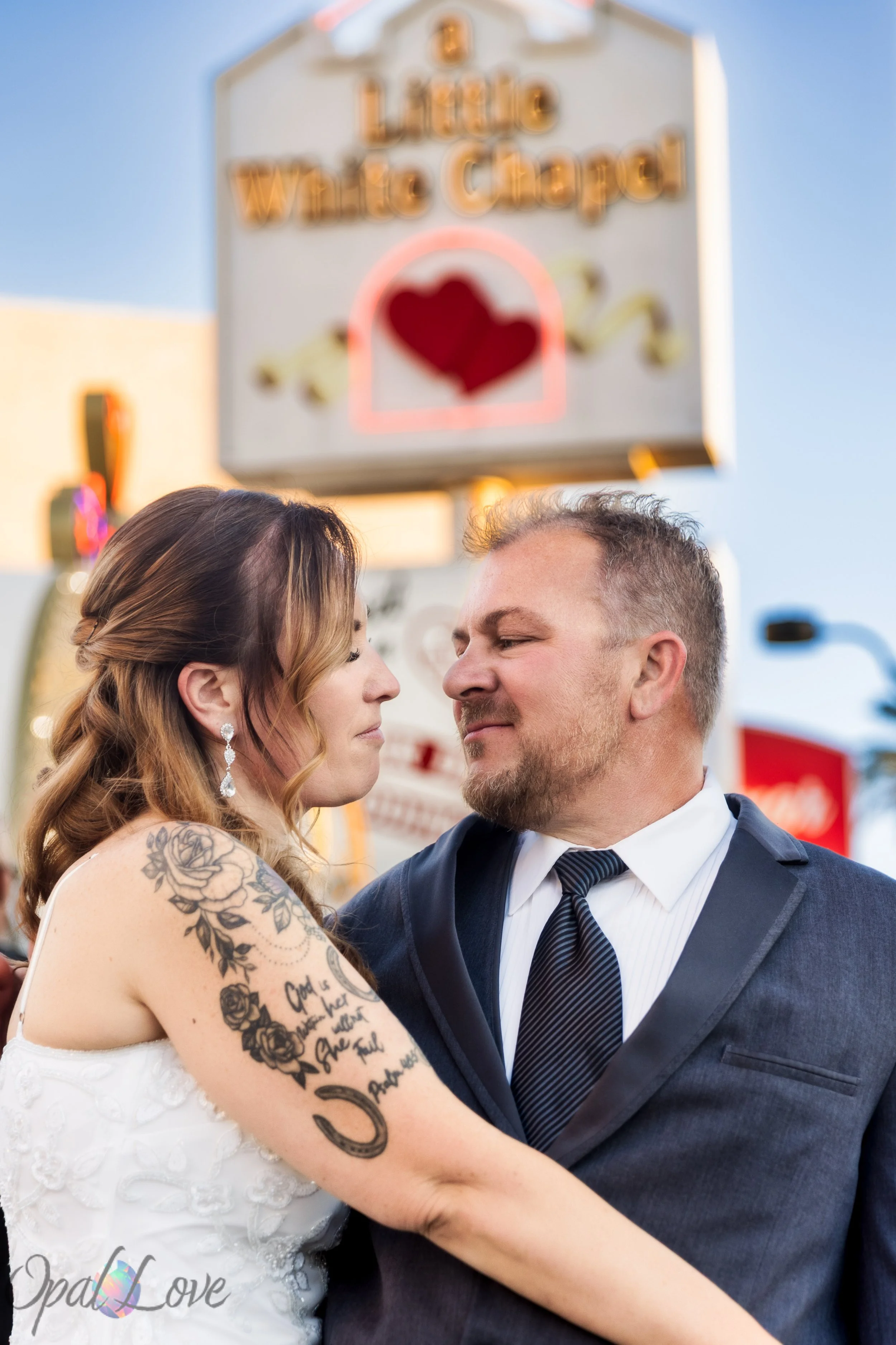 Bride and groom sharing a romantic portrait beneath the iconic A Little White Wedding Chapel sign.