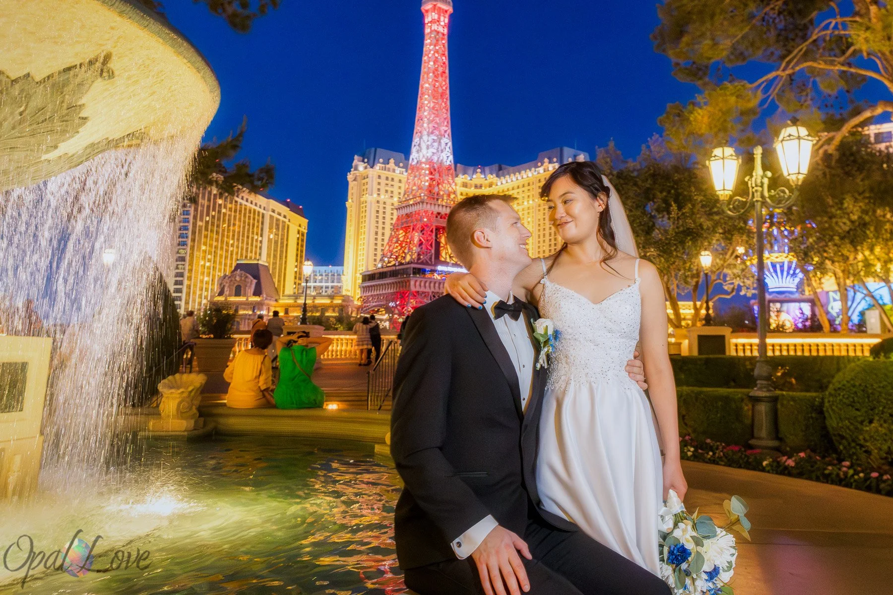 Newlyweds embrace beside a fountain with the Eiffel Tower behind them