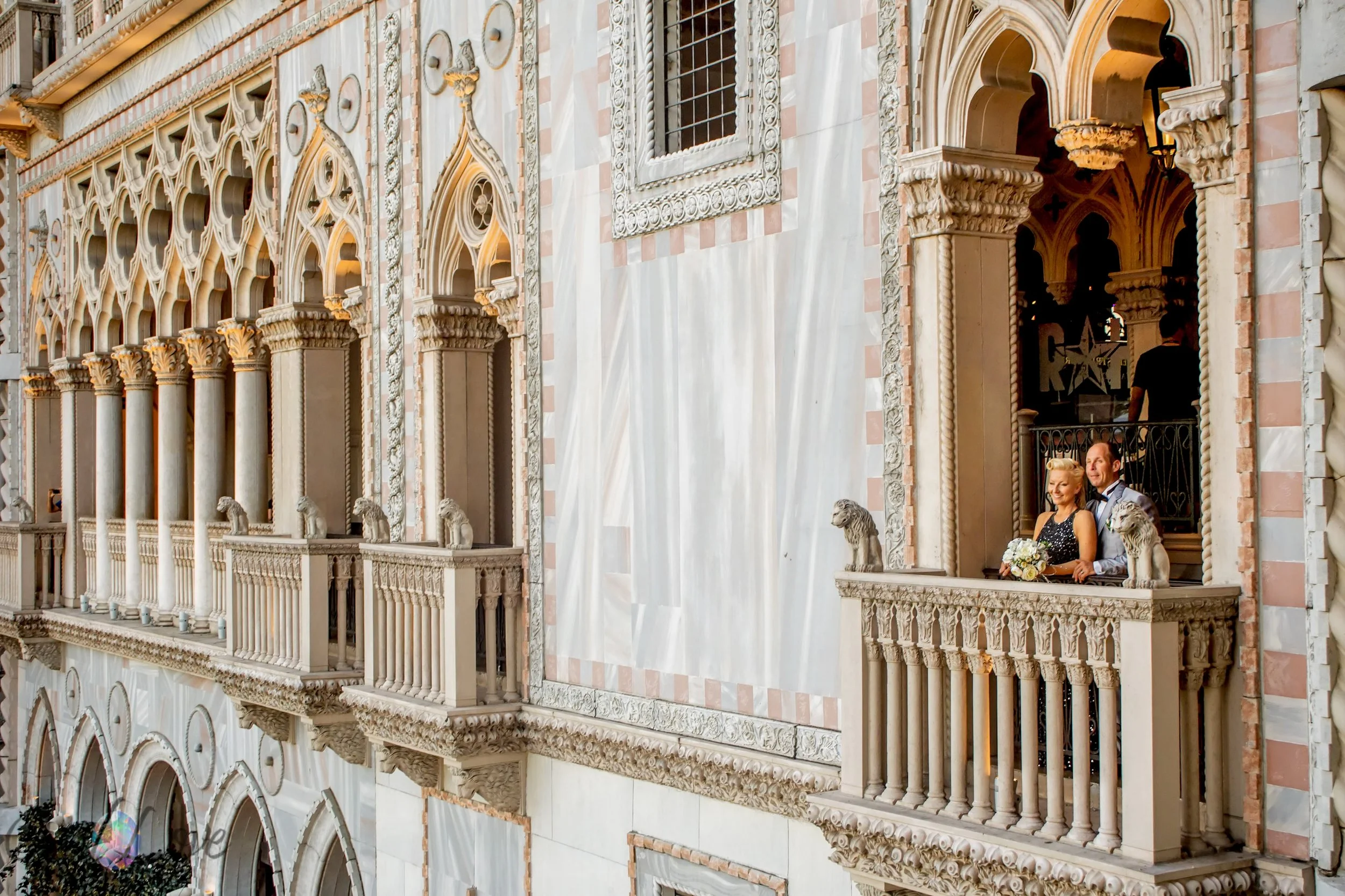 Couple standing on a Venetian balcony overlooking the replica architecture of Venice at The Venetian Las Vegas captured by Opal Love Photography.