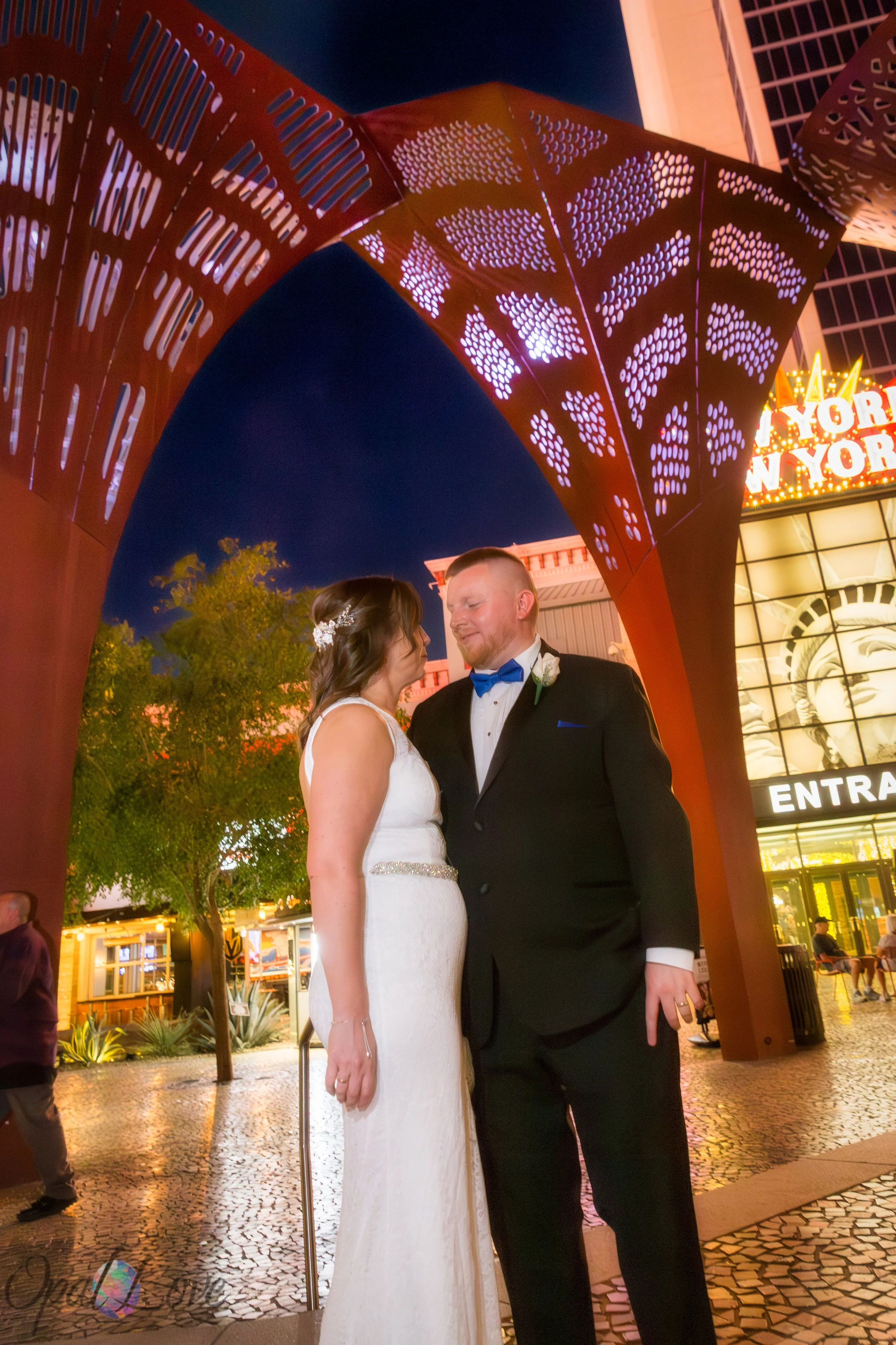 Bride and groom smiling at each other under the red metal arch at New York New York.