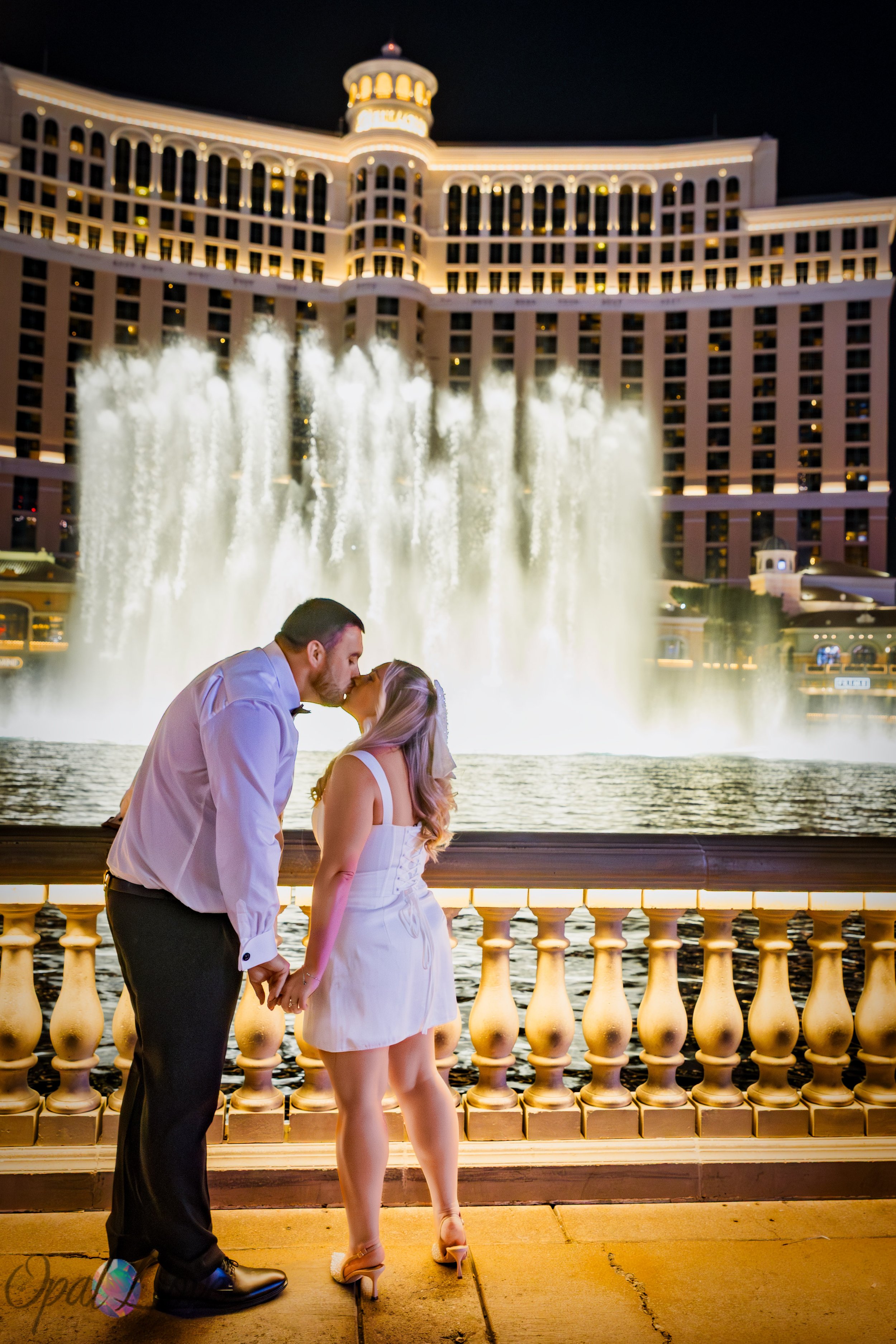 Couple kissing in front of the Bellagio Fountains during a Las Vegas honeymoon photo session.
