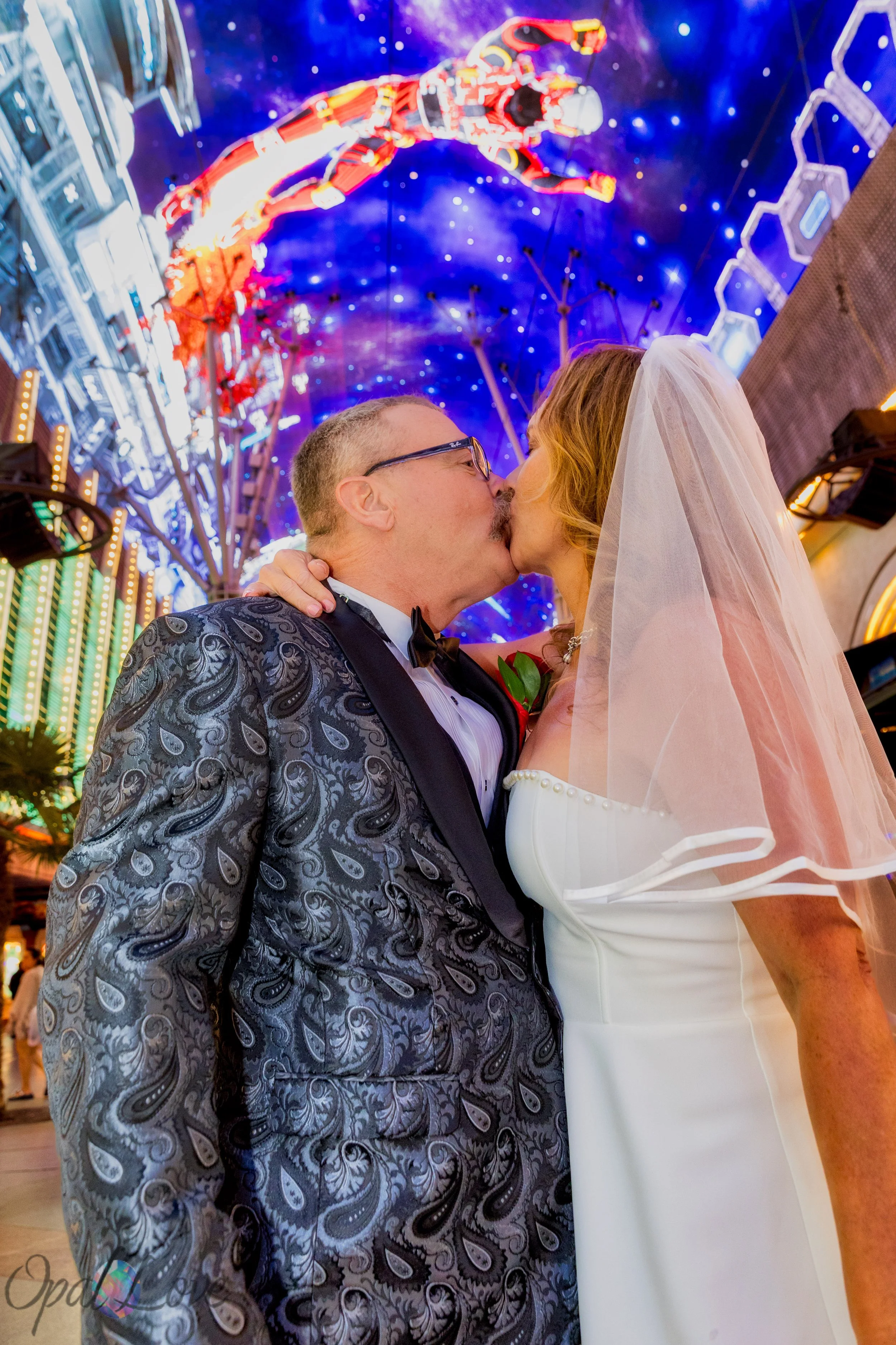 Bride and groom kissing beneath the colorful Fremont Street Experience canopy during their Las Vegas wedding photo tour.