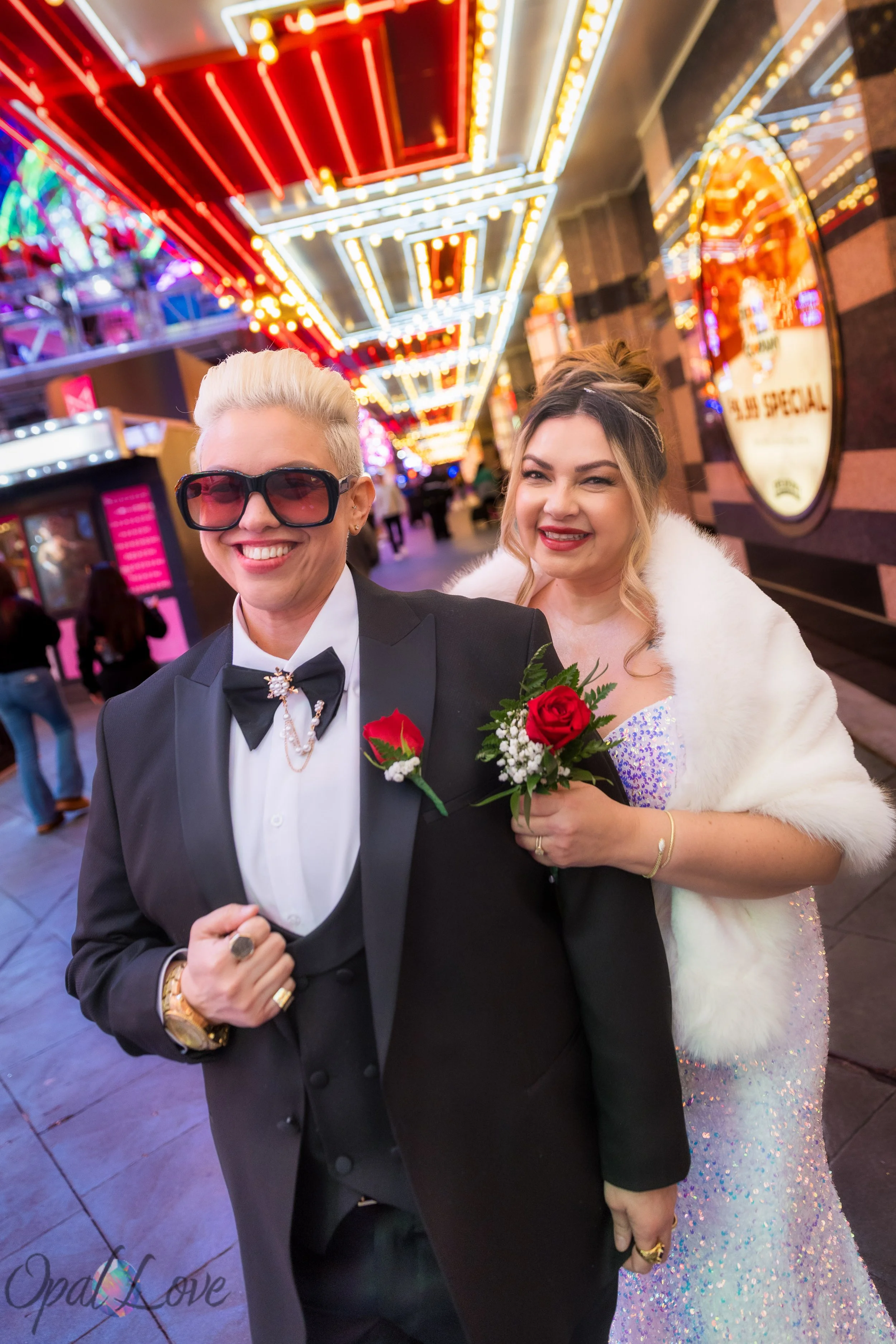 Anniversary couple walking beneath the bright Fremont Street Experience canopy in downtown Las Vegas.