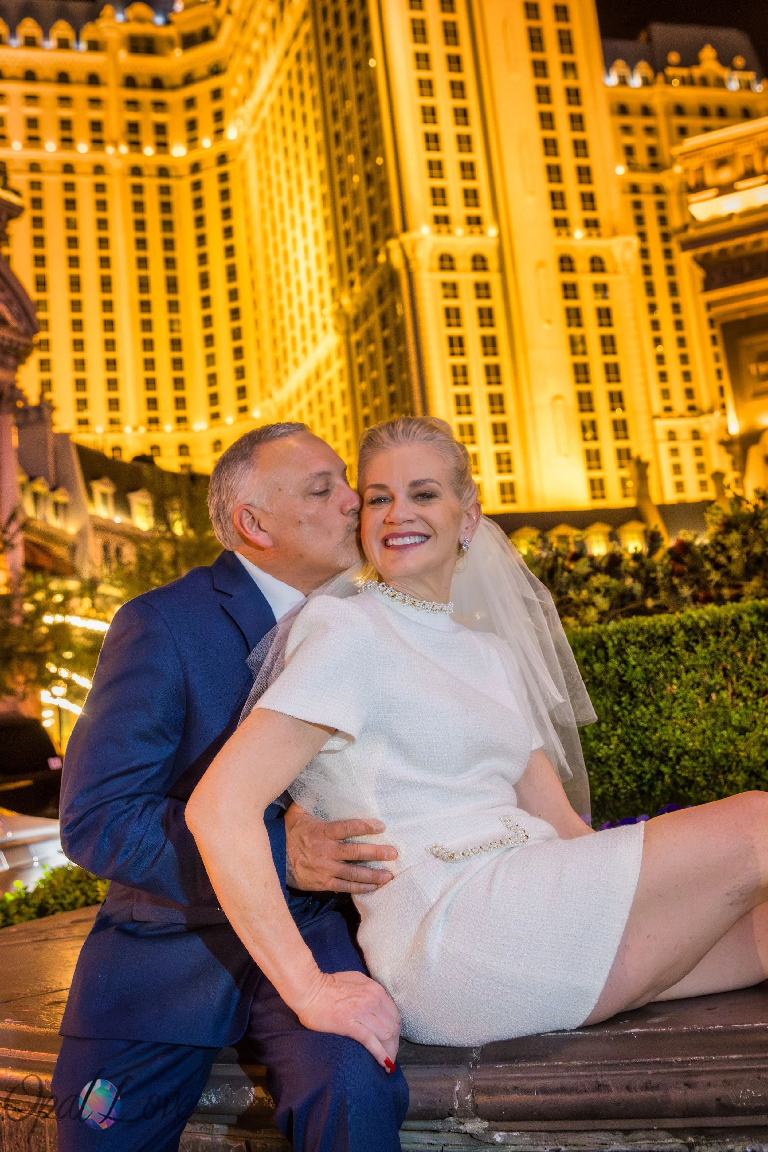 Bride and groom posing under glowing Paris Las Vegas sign