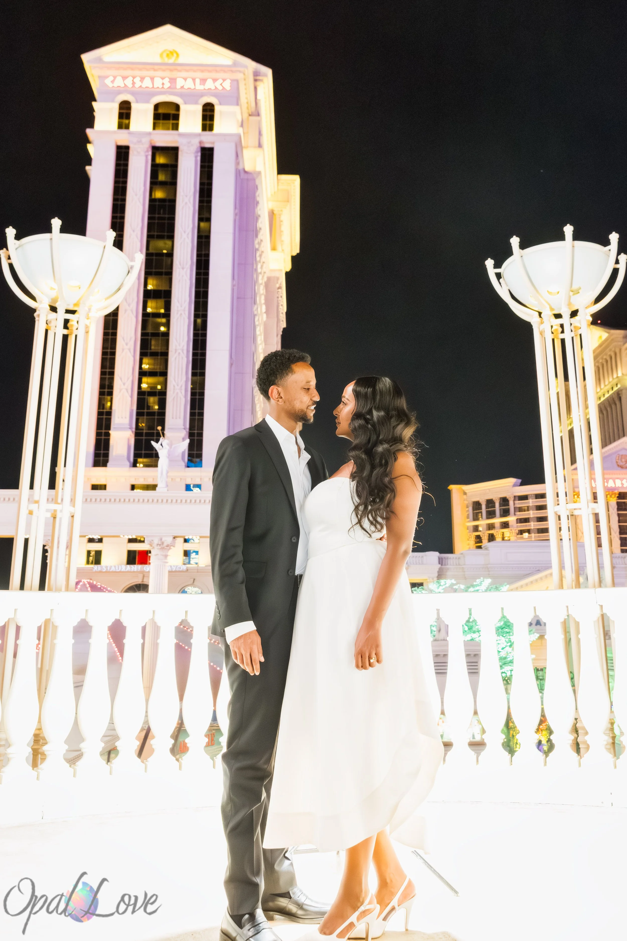 Wedding portraits of Menna and Yoseph beneath the illuminated architecture of Caesars Palace on the Las Vegas Strip.