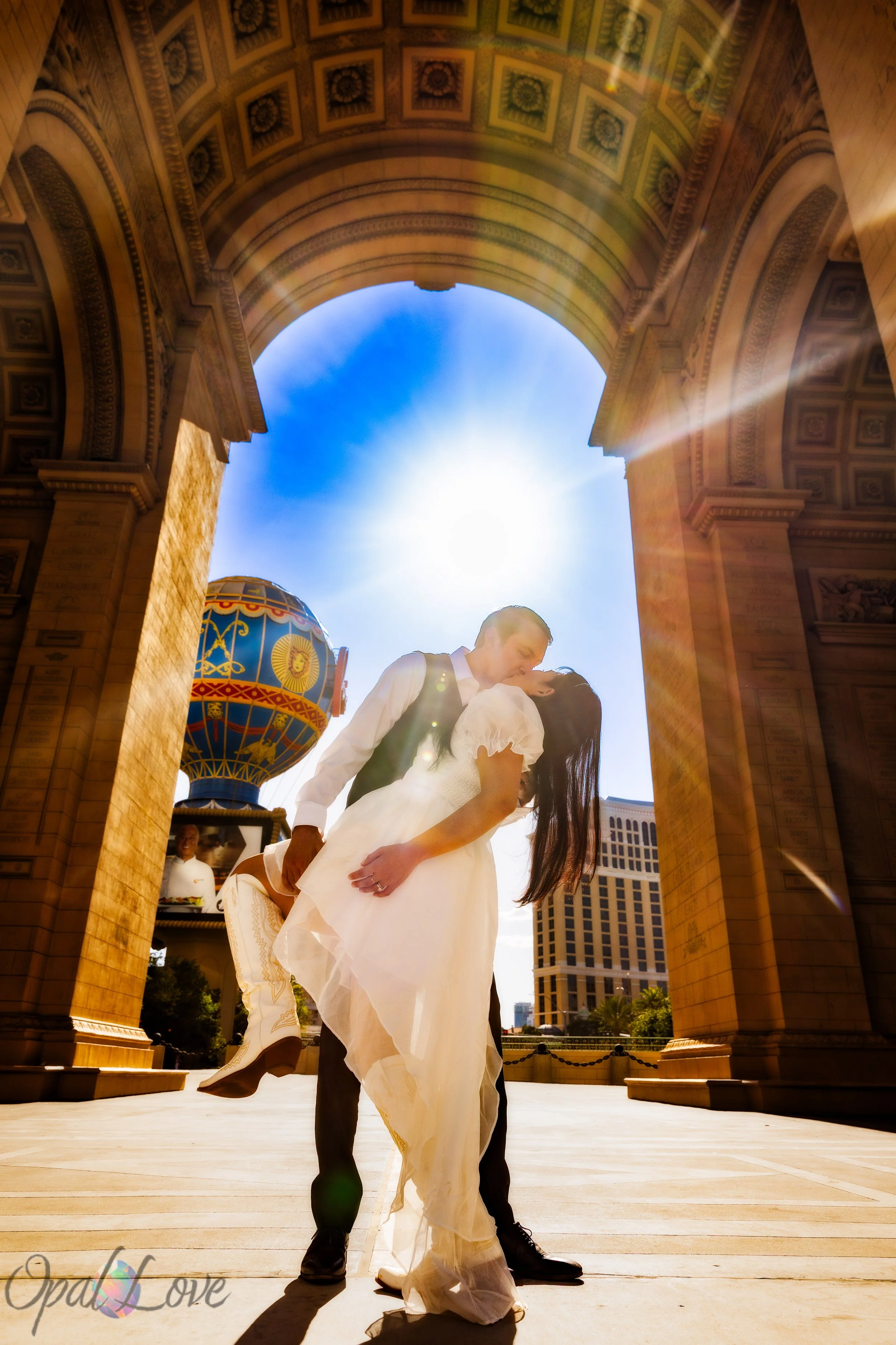 Bride and groom kissing beneath the Paris Las Vegas archway during wedding portraits