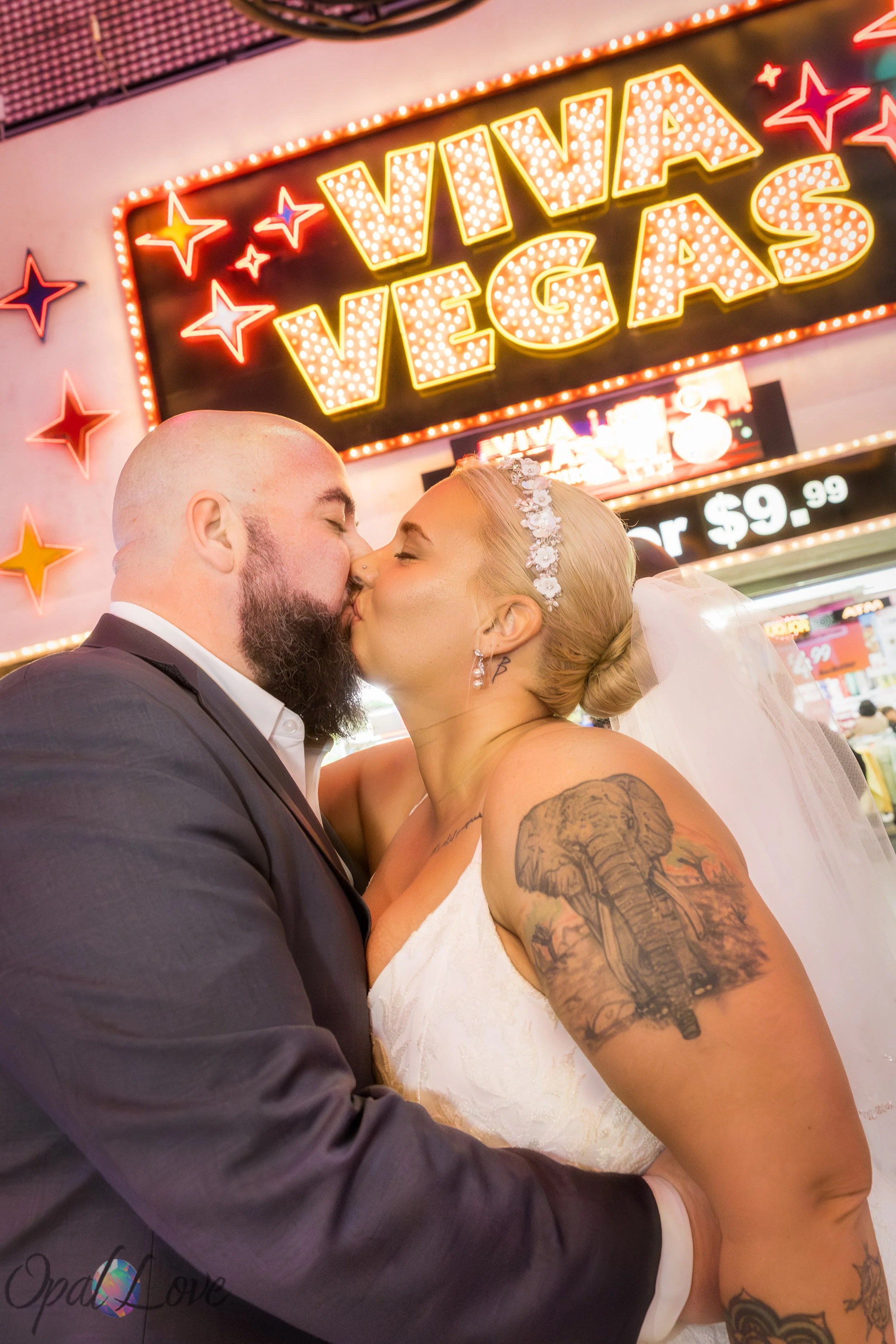 Couple kissing beneath the bright Viva Vegas lights in downtown Las Vegas.