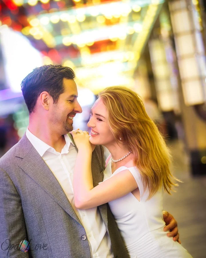 Couple smiling together beneath the colorful lights of Fremont Street in downtown Las Vegas.