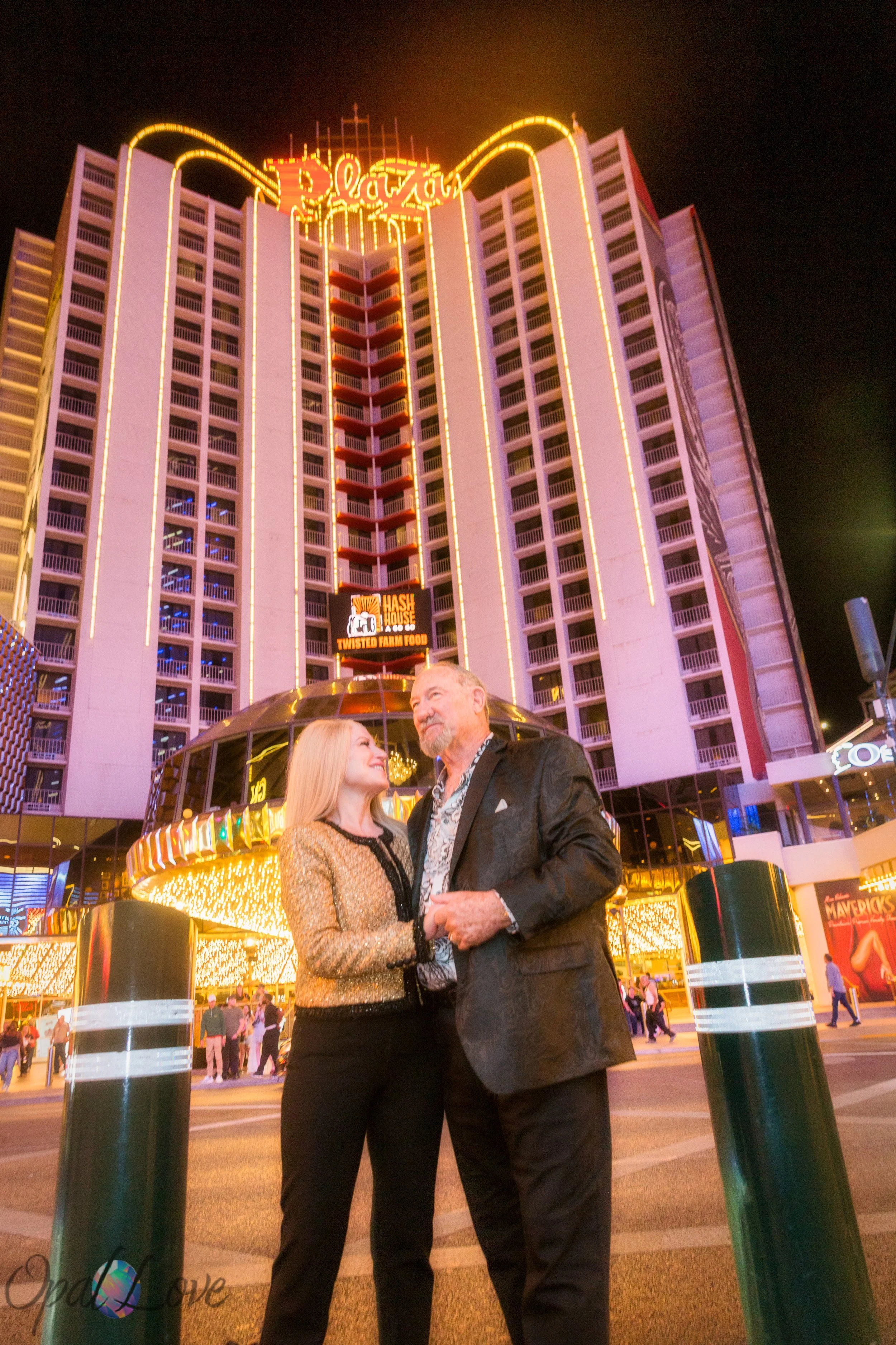 Couple holding hands with the Plaza Hotel lit up behind them.