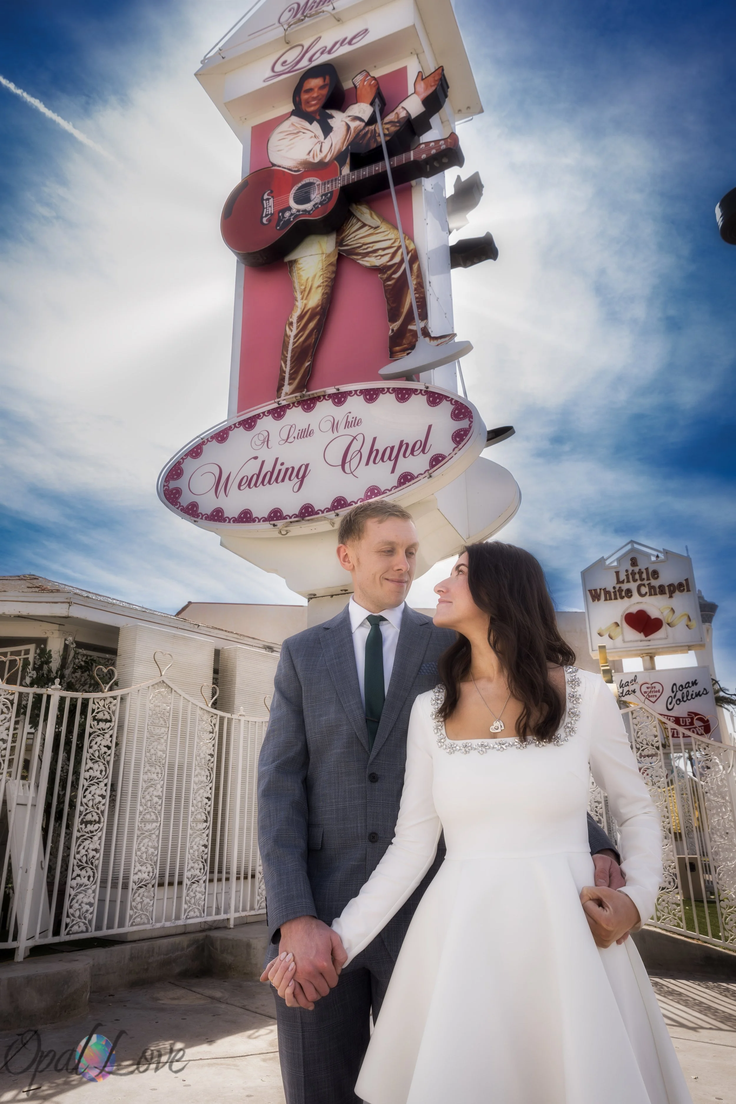 Couple posing beneath the Elvis sign at A Little White Wedding Chapel after their Las Vegas wedding ceremony.