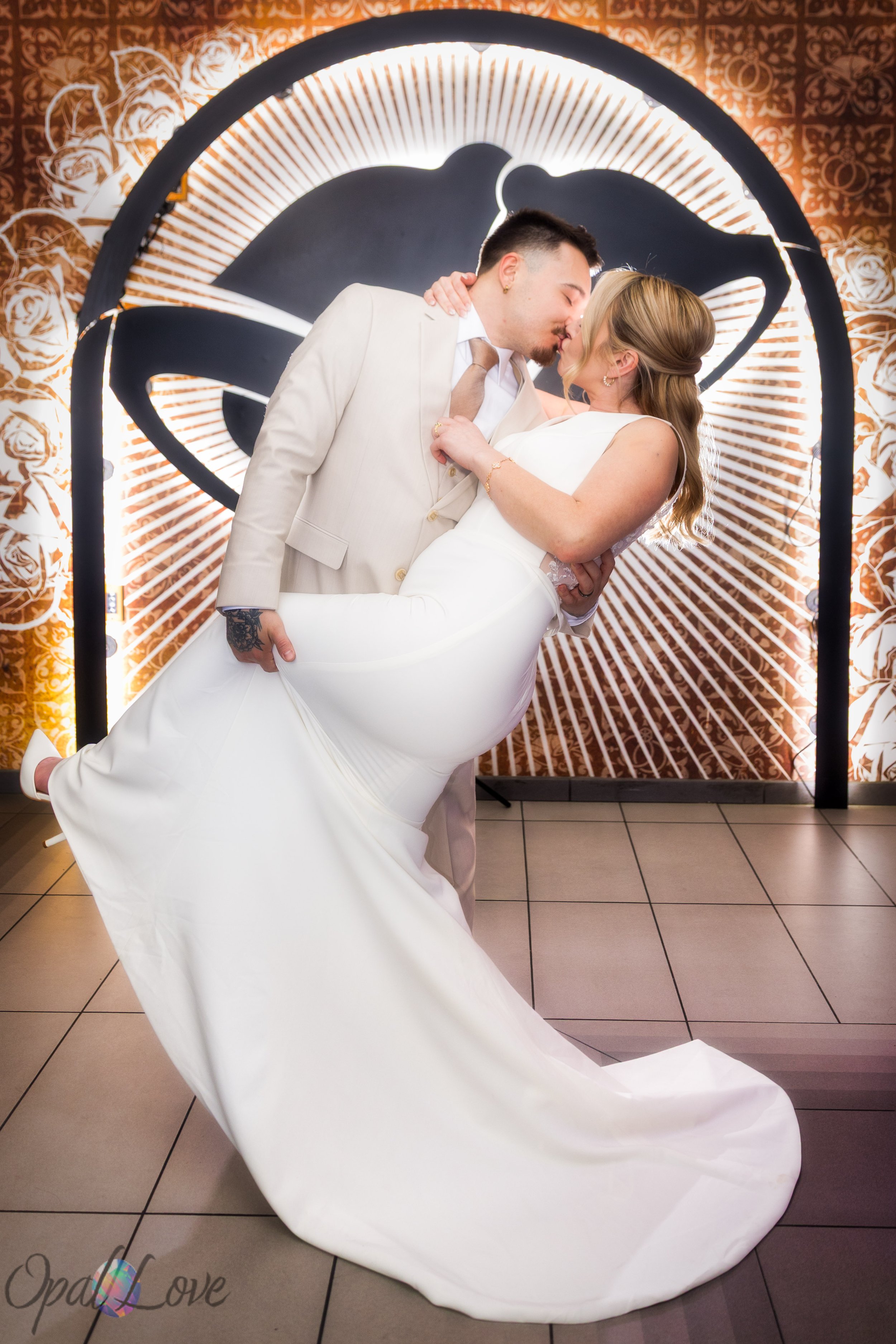 Groom dipping bride in front of glowing Taco Bell Cantina backdrop during fun Las Vegas wedding photos.