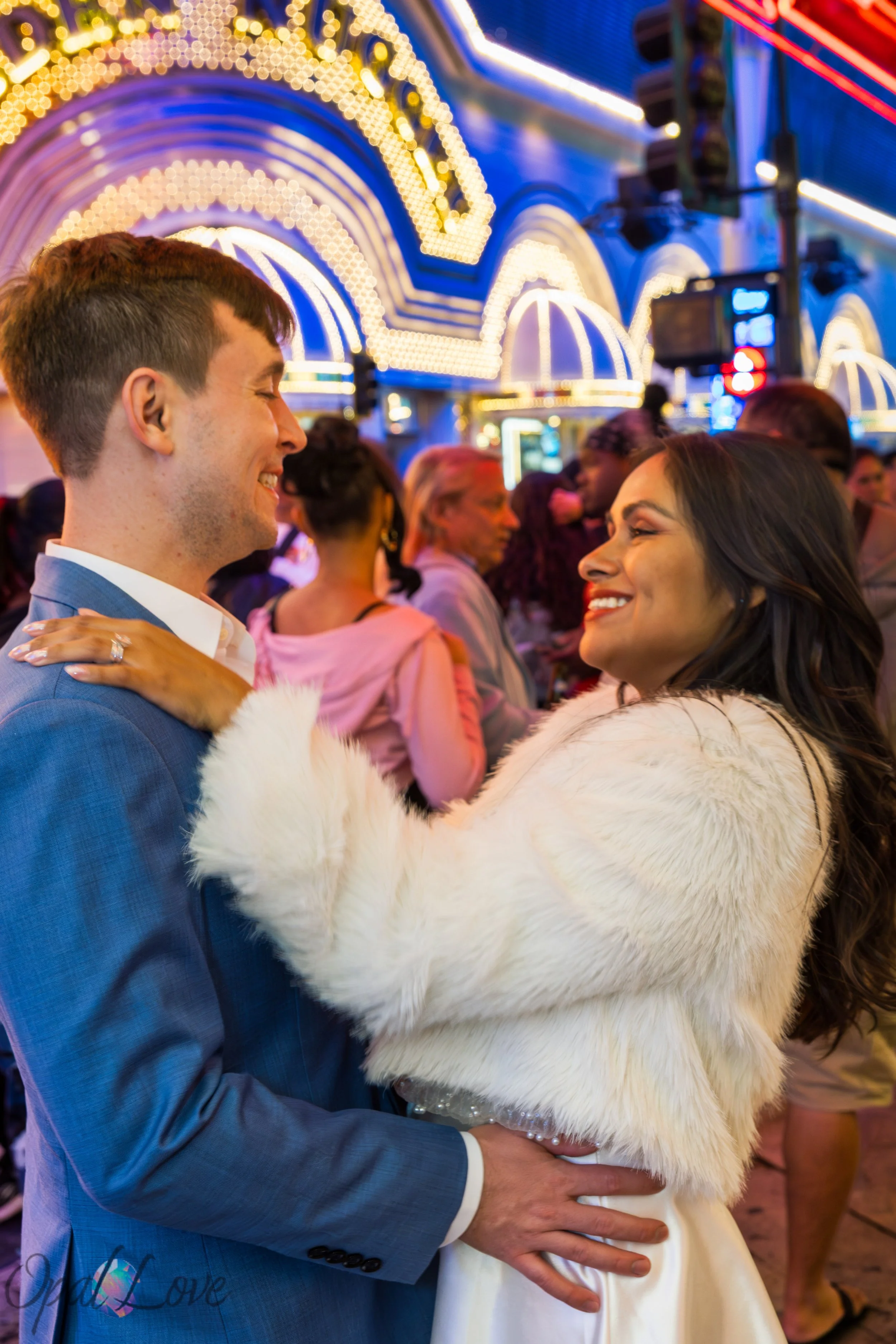 Couple smiling together surrounded by neon lights and crowd on Fremont Street