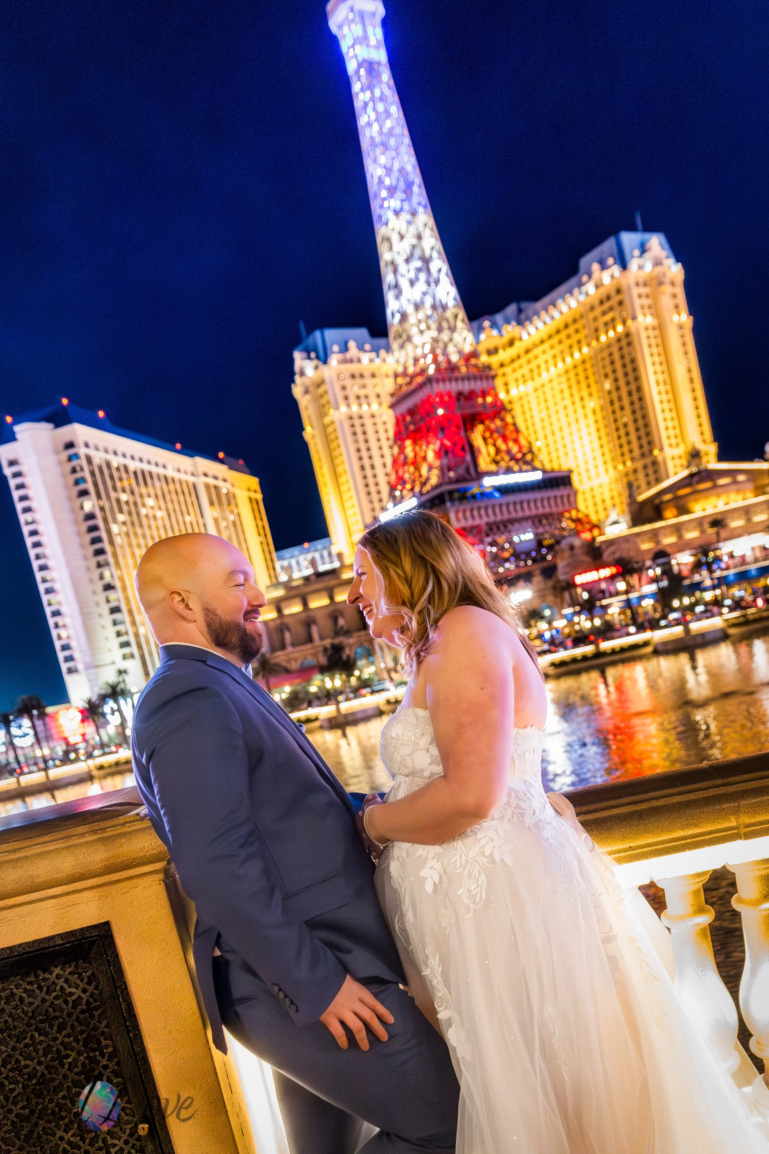 Groom kissing bride with the Bellagio lights and fountains glowing behind them in Las Vegas.