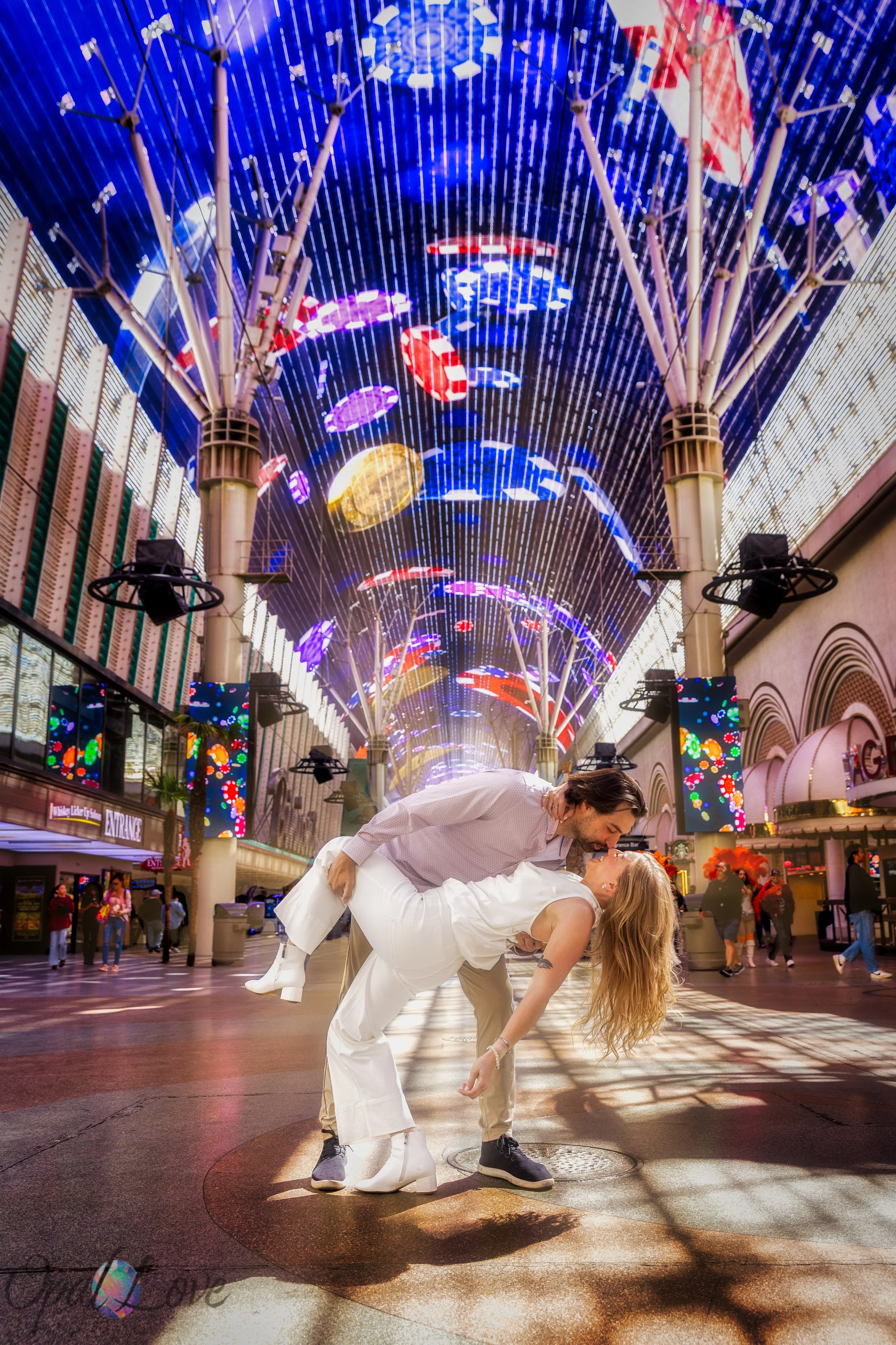 Couple dipping into a kiss beneath the colorful Fremont Street Experience LED canopy in downtown Las Vegas.