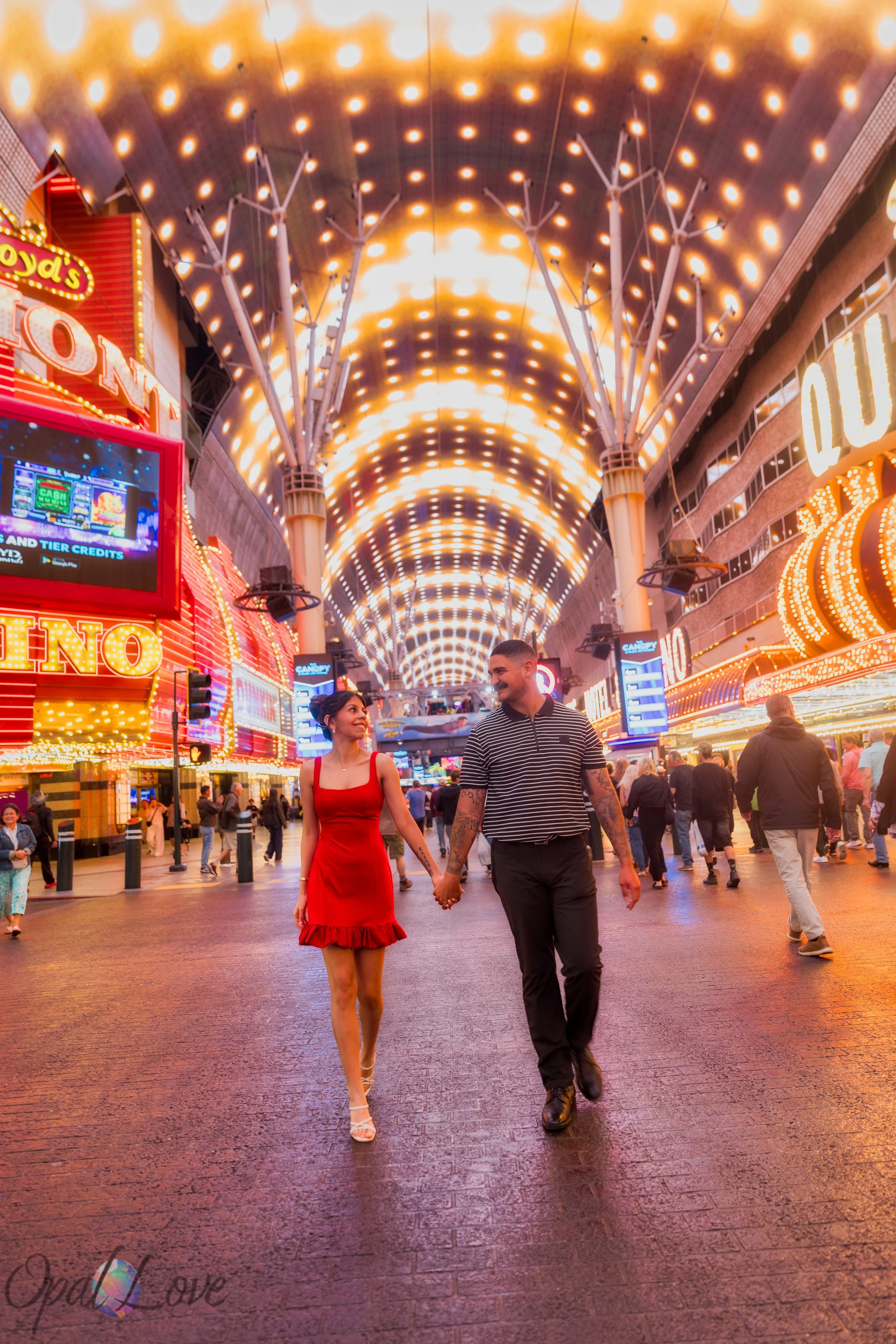 Couple walking hand in hand under Fremont Street canopy lights in Las Vegas