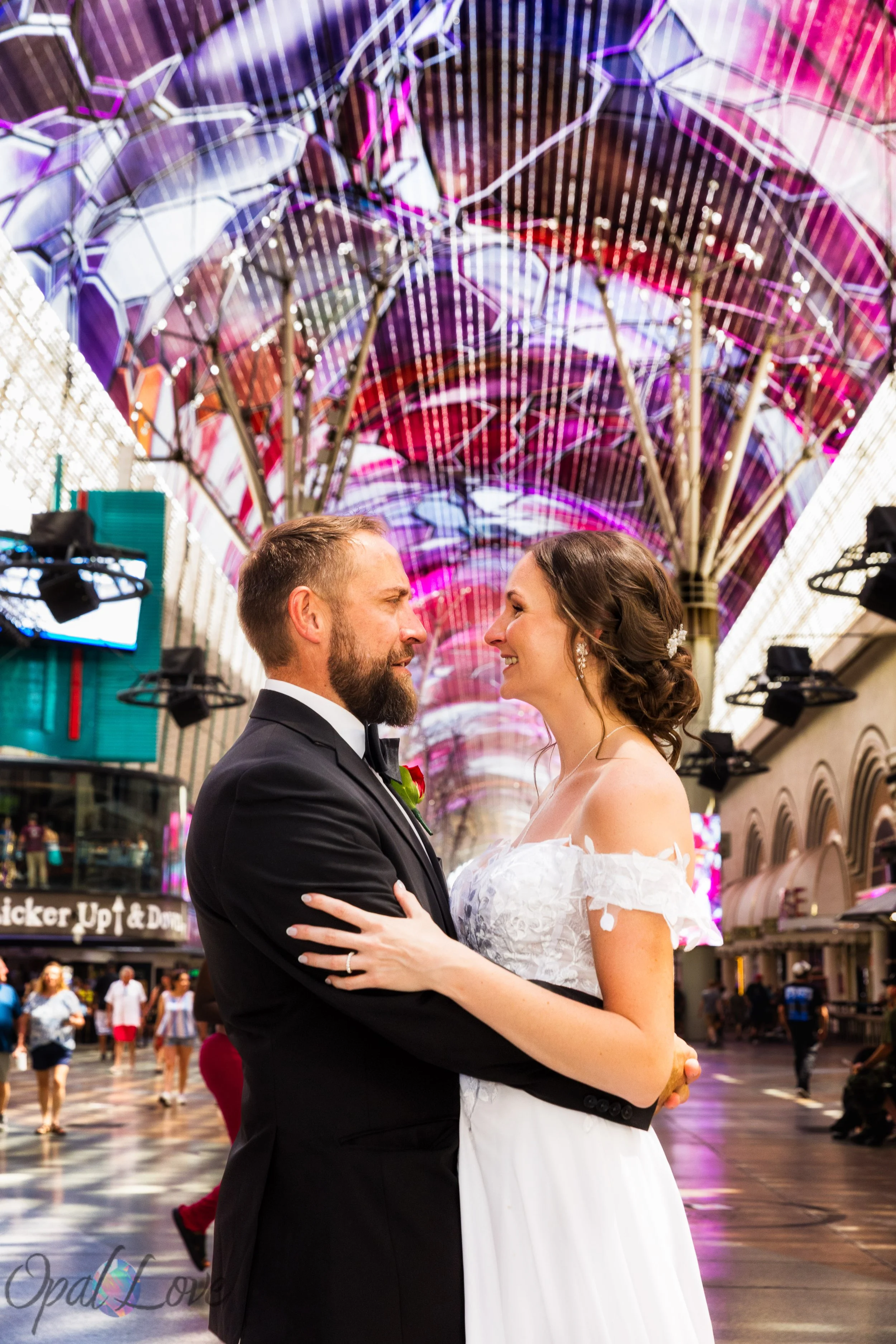 Kari and Rickie embracing beneath the colorful Fremont Street Experience canopy during their Las Vegas wedding photo session.