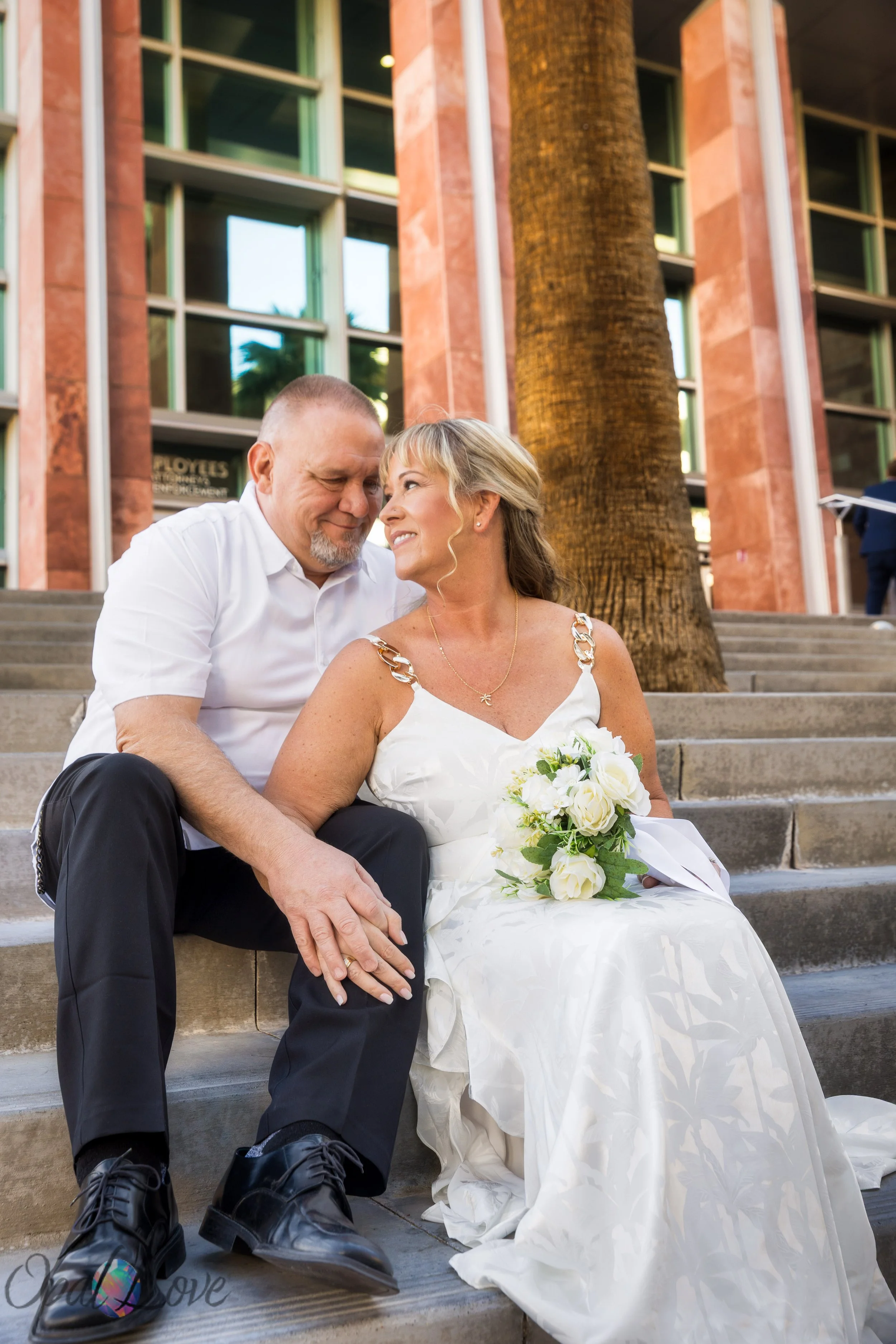 Bride and groom sitting closely together on the downtown Las Vegas courthouse steps after their civil ceremony.