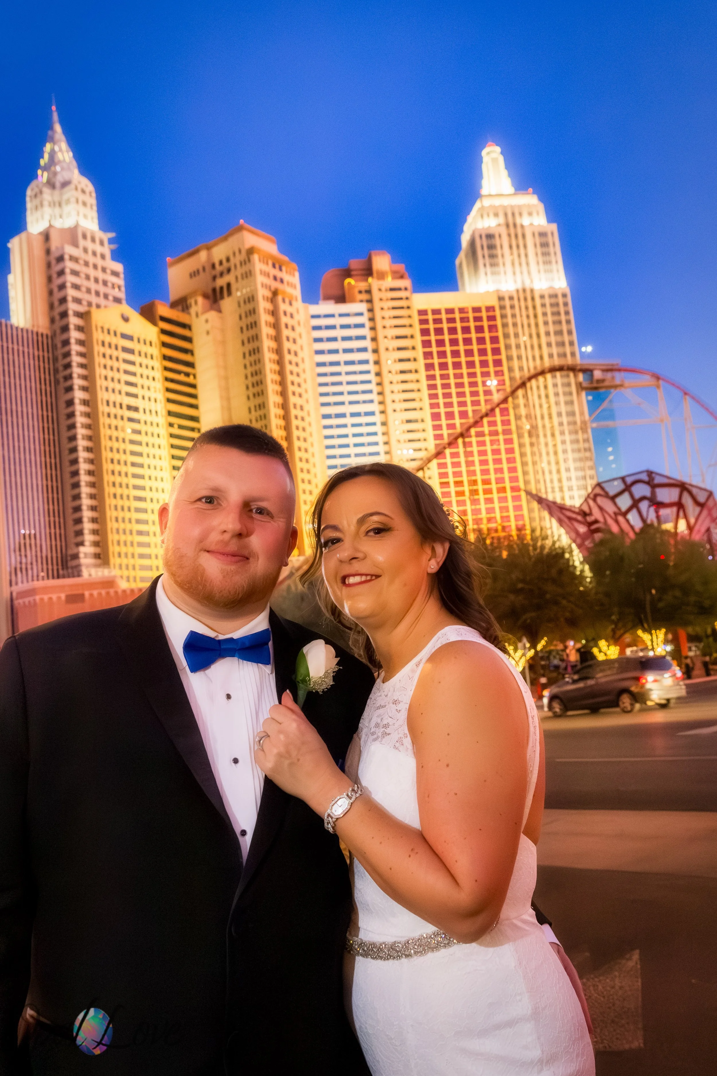 Couple posing together with the New York New York skyline lit up behind them.