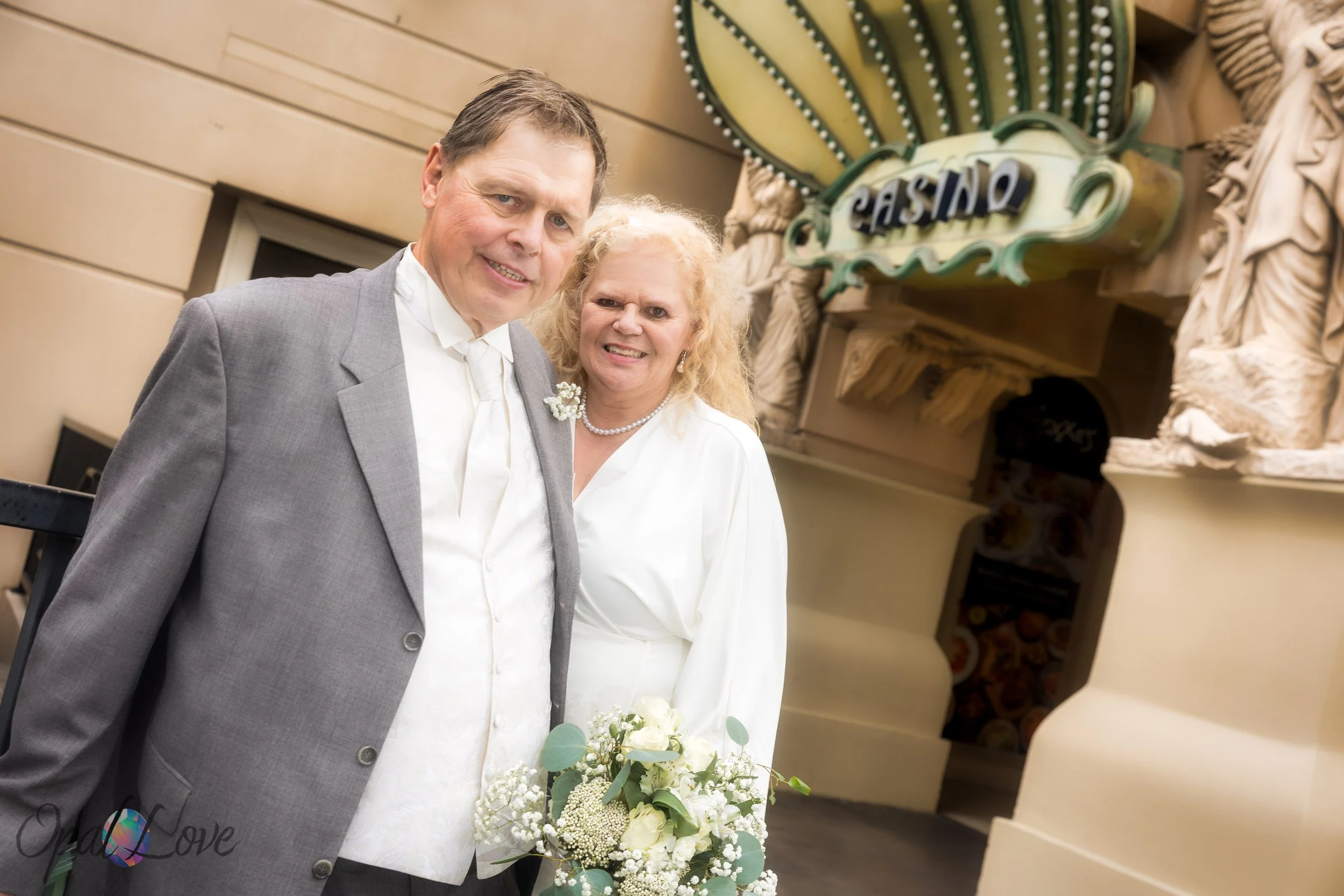Couple posing by Paris Las Vegas casino entrance holding bouquet