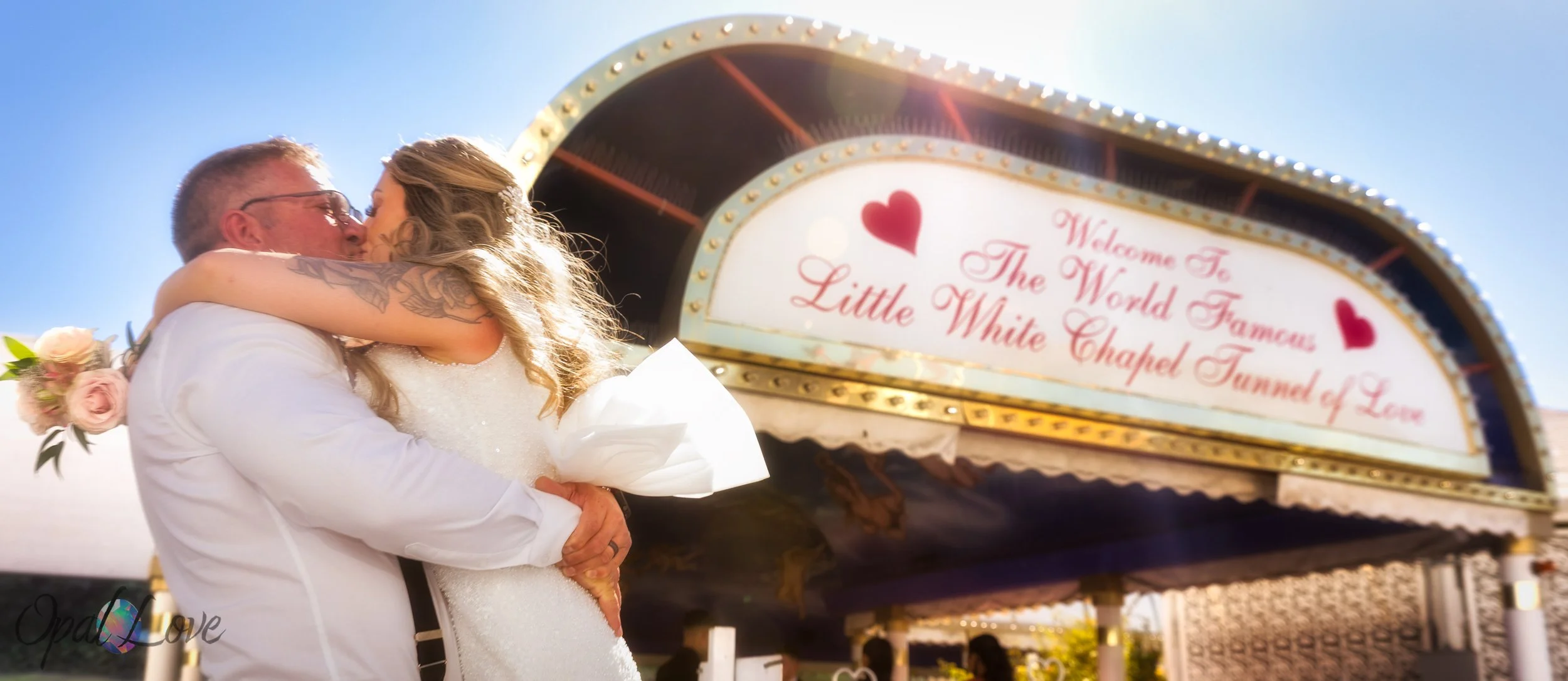 Couple kissing under Tunnel of Love sign at Little White Wedding Chapel.