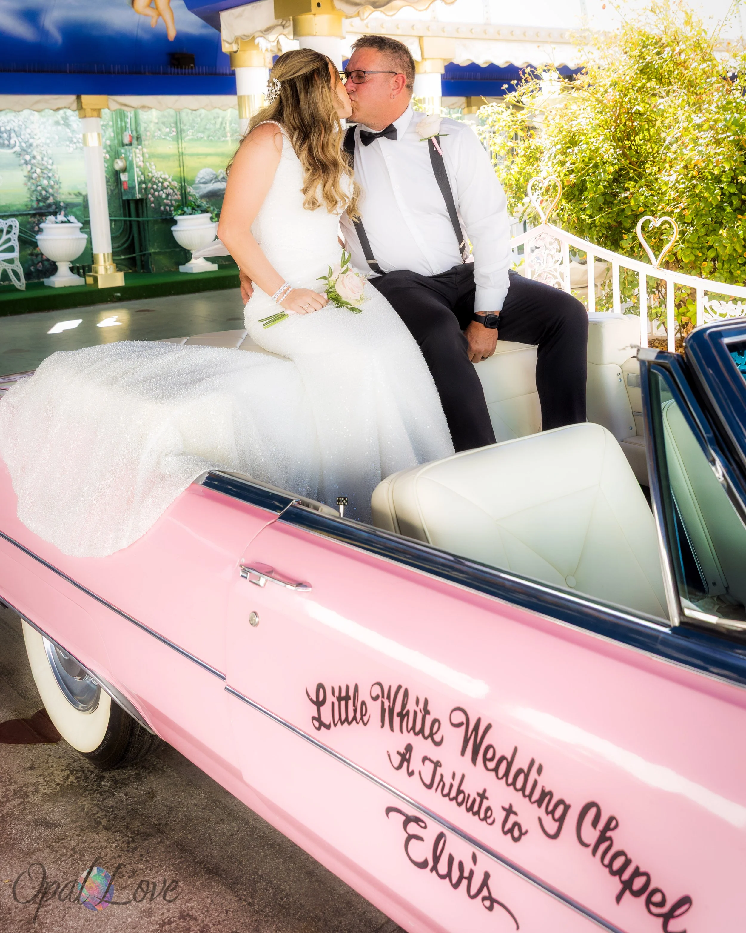 Bride and groom kissing in pink Cadillac at Little White Wedding Chapel in Las Vegas.