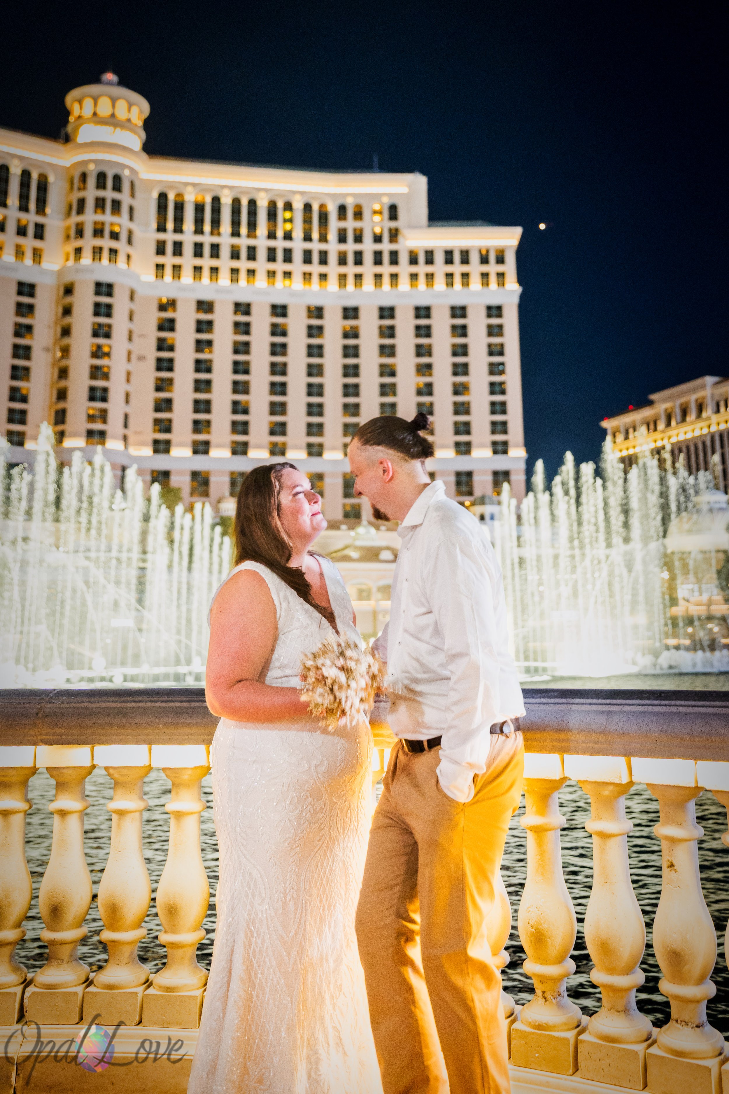 Couple sharing a quiet moment with the Bellagio Fountains and Bellagio hotel illuminated behind them at night.