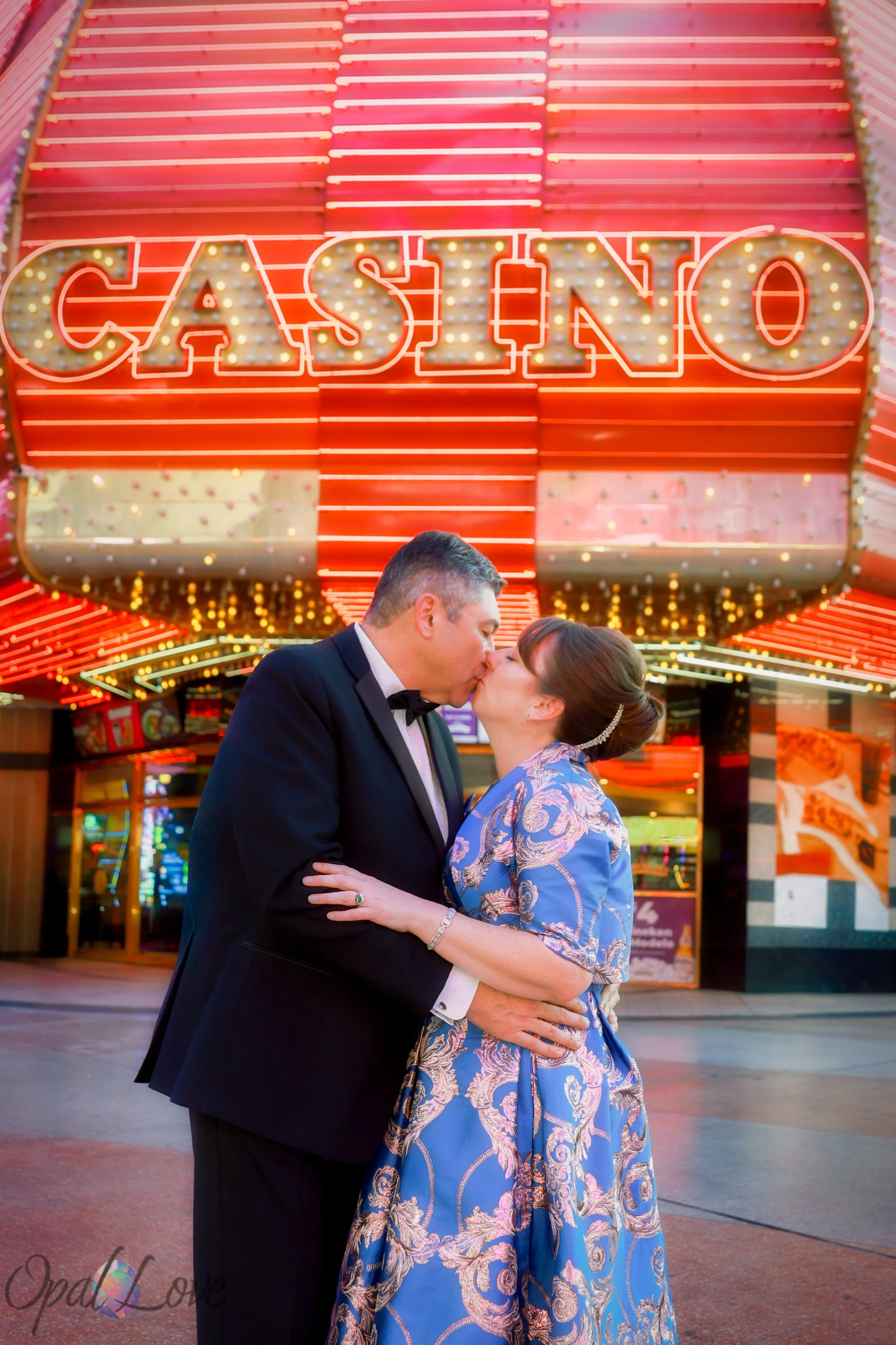 Couple kissing in front of a bright Casino marquee in downtown Las Vegas.