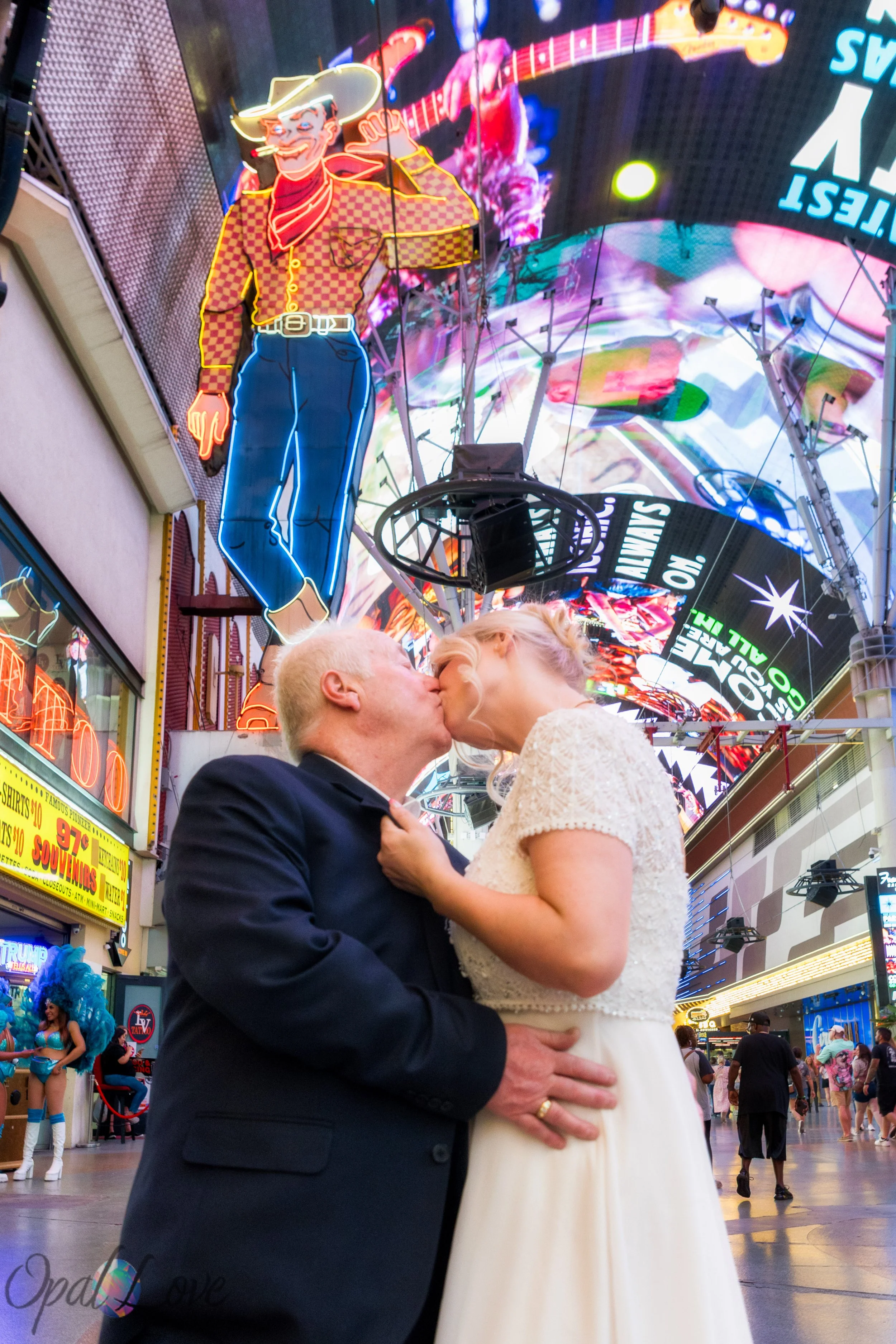 Bride and groom kissing beneath the classic neon cowboy sign in downtown Las Vegas.