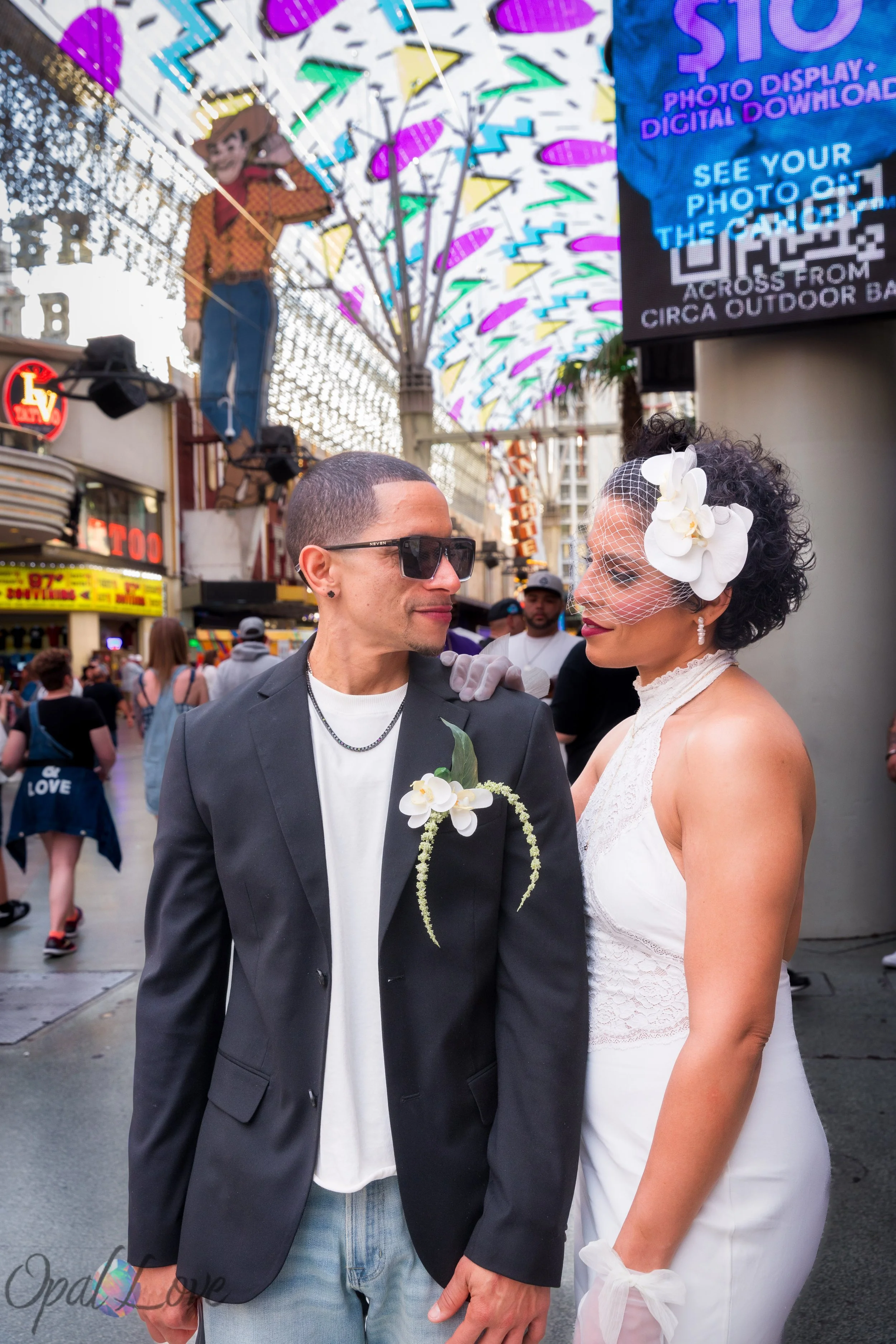 Couple posing together on Fremont Street surrounded by neon lights and downtown Las Vegas crowds.
