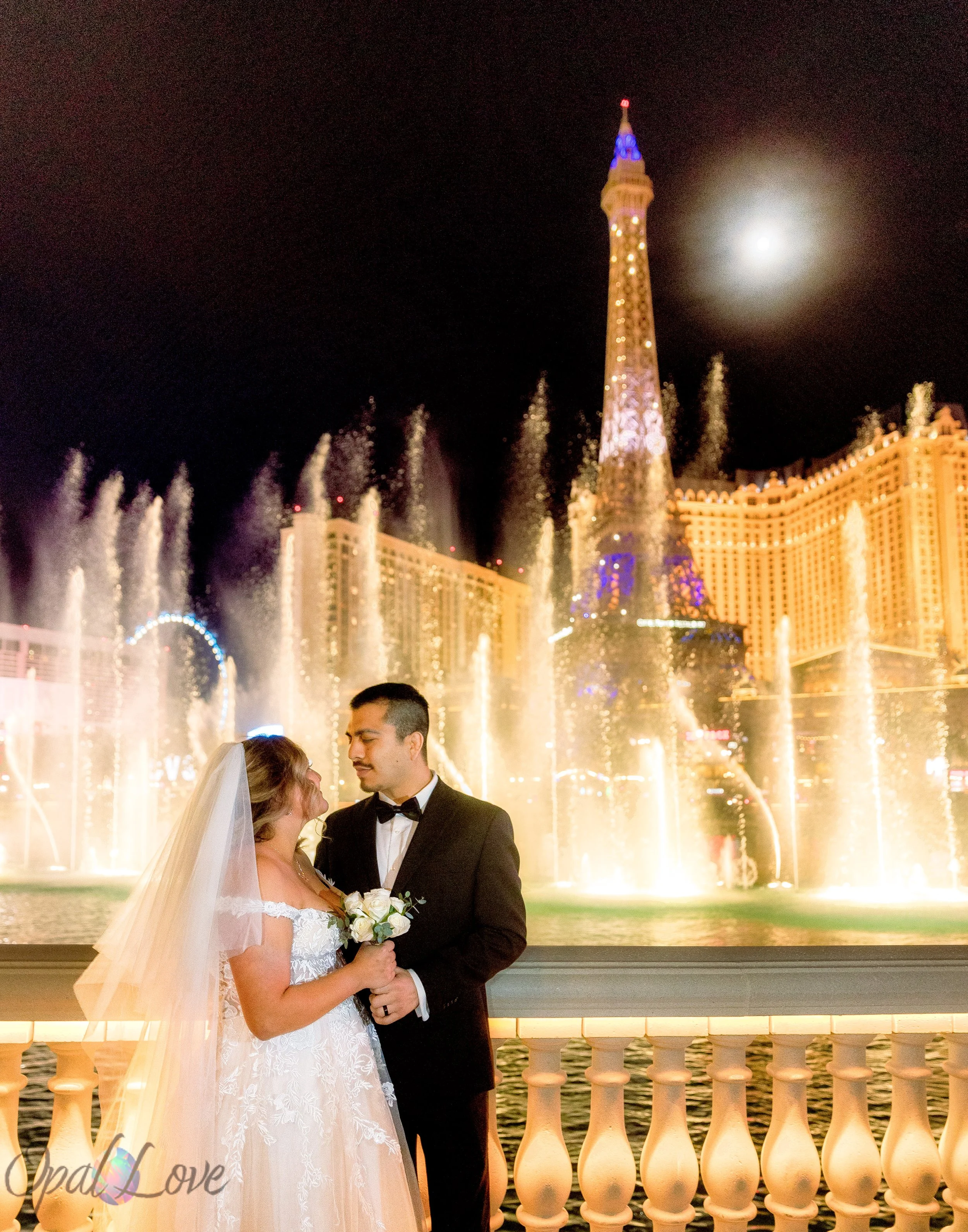 Couple eloping in Las Vegas sharing a quiet moment in front of the Bellagio fountains at night, captured by a Las Vegas elopement photographer