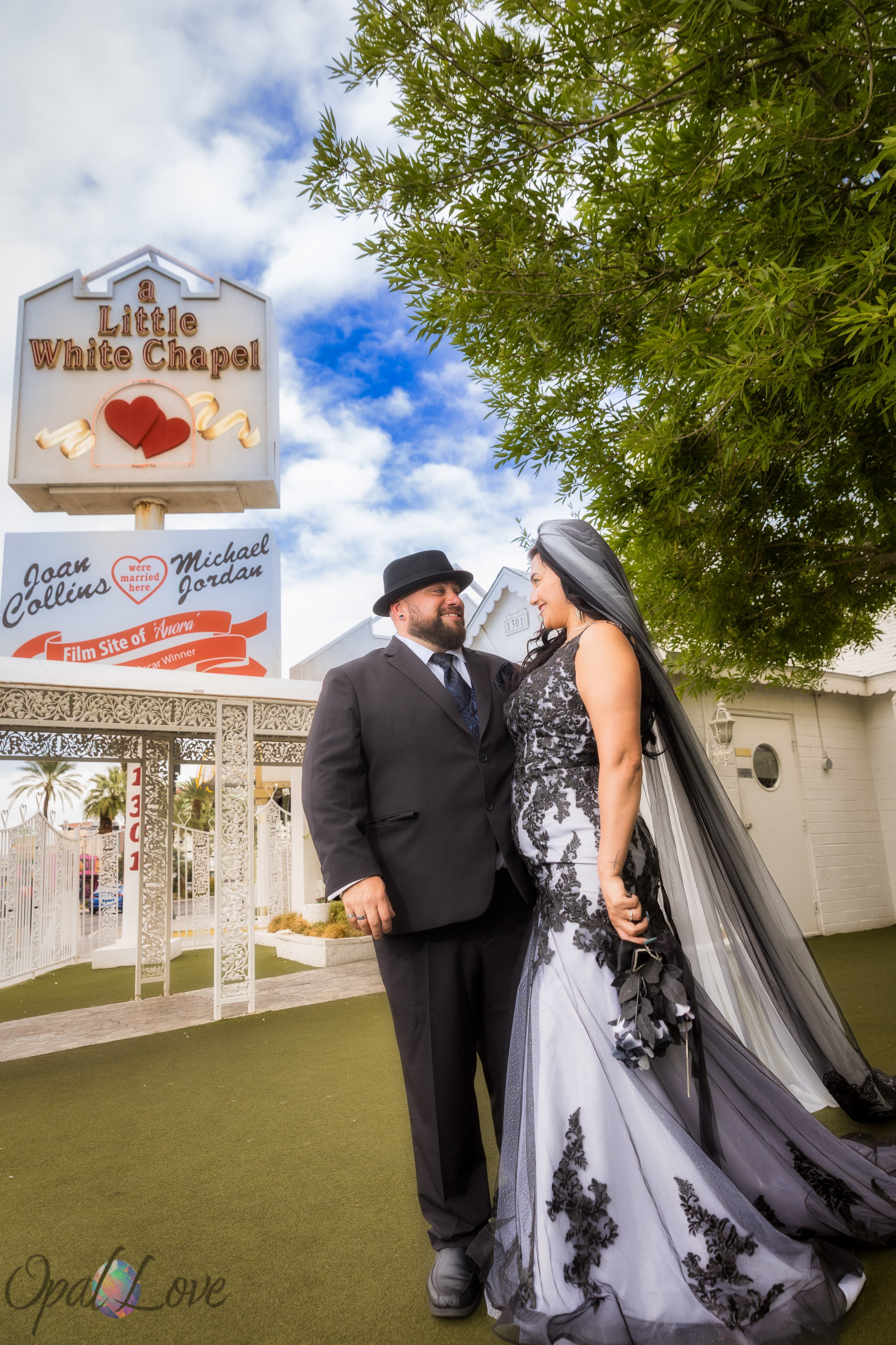 Bride and groom standing beneath the Little White Chapel sign during their Las Vegas wedding.