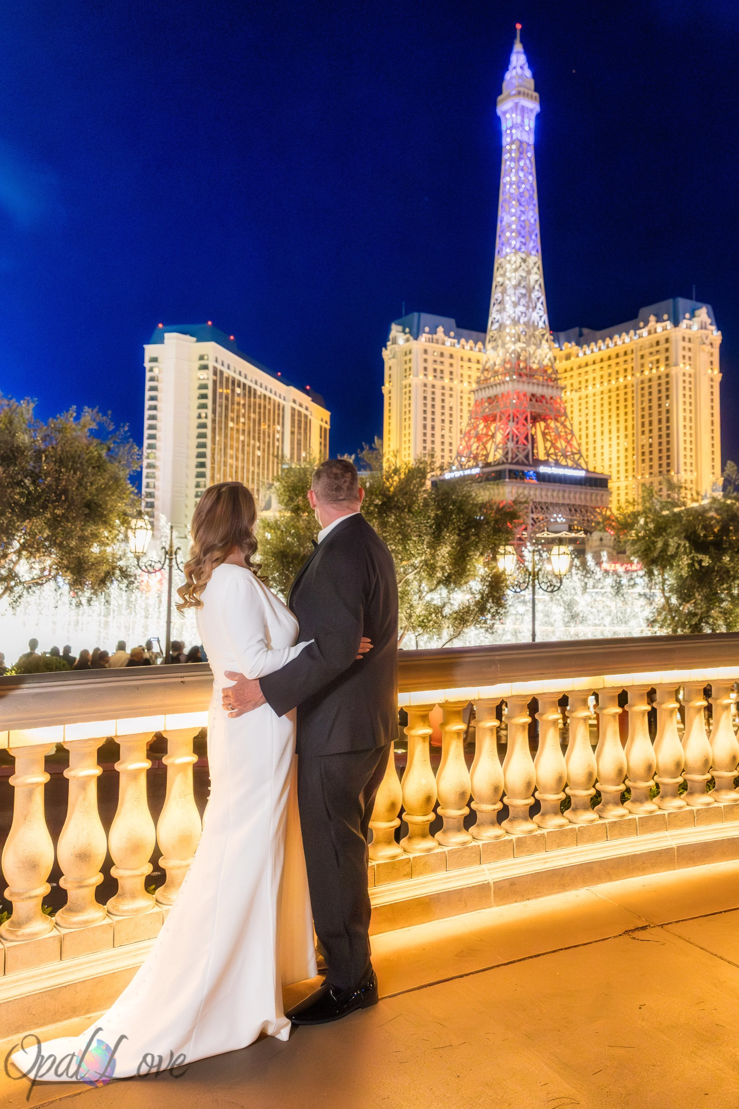 Couple overlooking Bellagio fountains with Las Vegas Strip lights at night