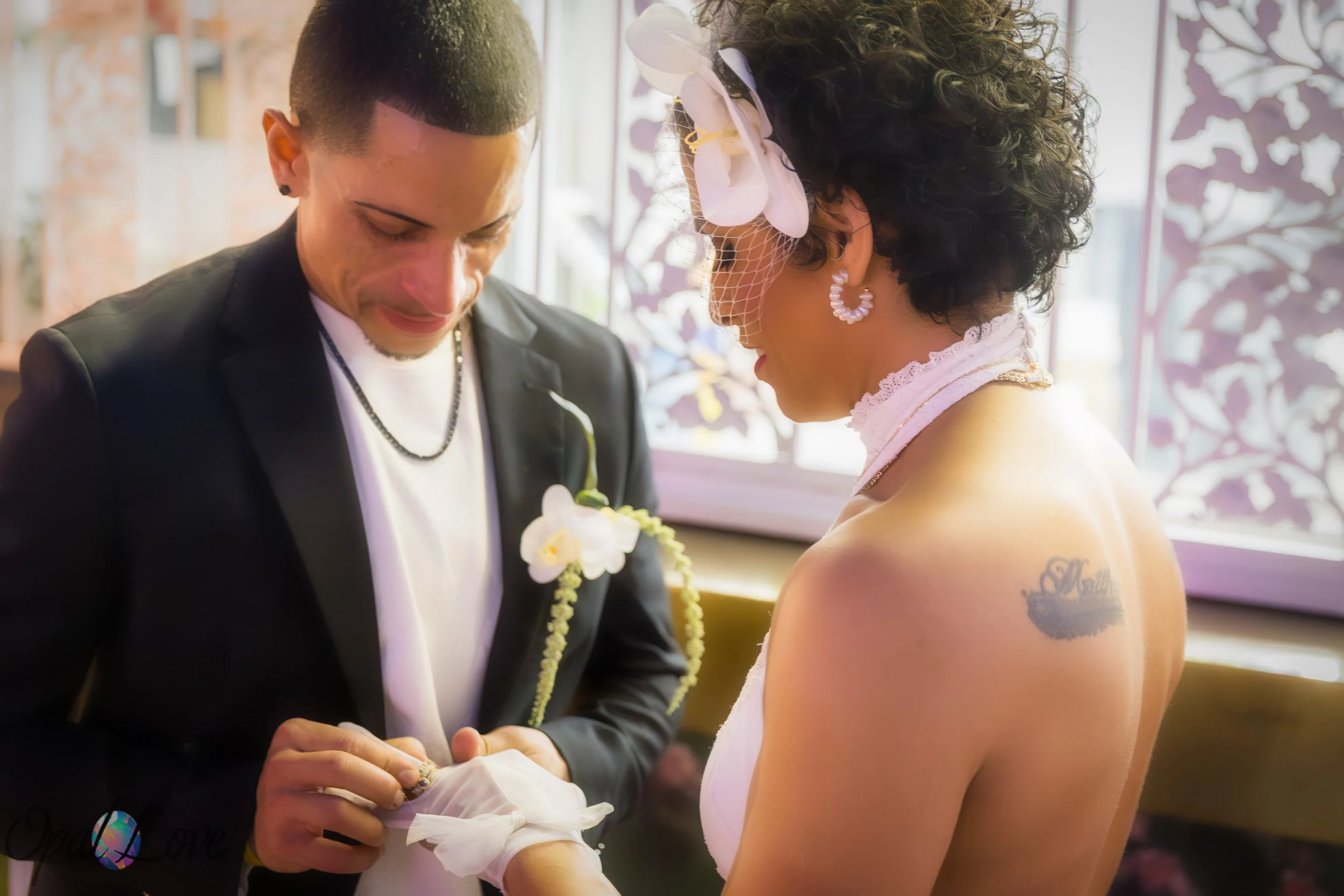 Couple exchanging rings, with the bride wearing white gloves and a small veil.